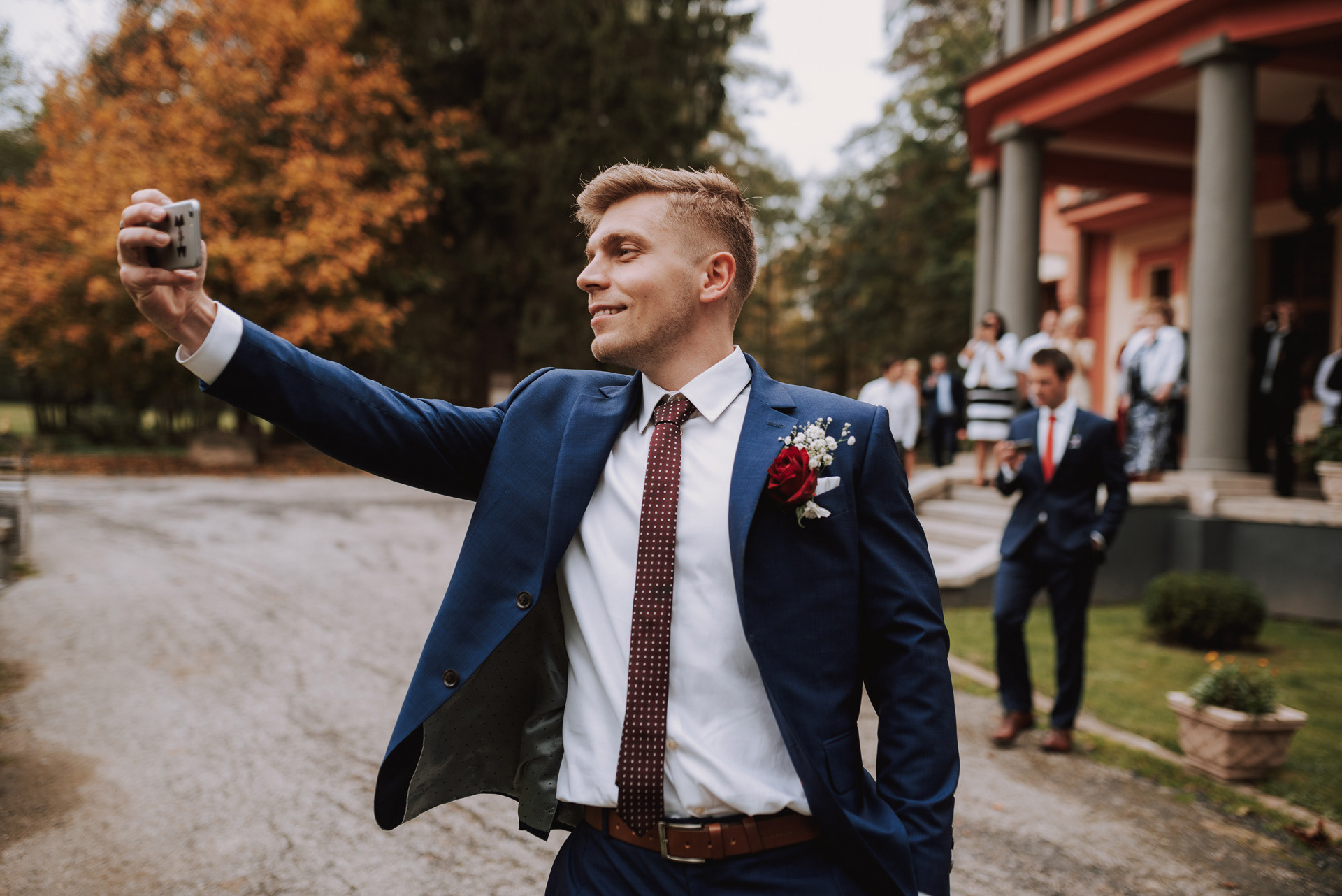 ženich si na mobil fotí nevěstu přichystanou k házení kyticí