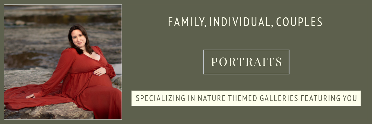 woman in flowy dress sitting on rocks holding stomach