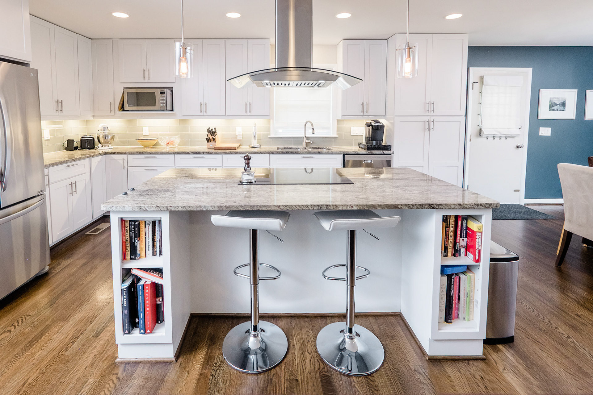 An induction range and dramatic hood take center stage. Plenty of shelves for cookbooks are incorporated in the generous island.