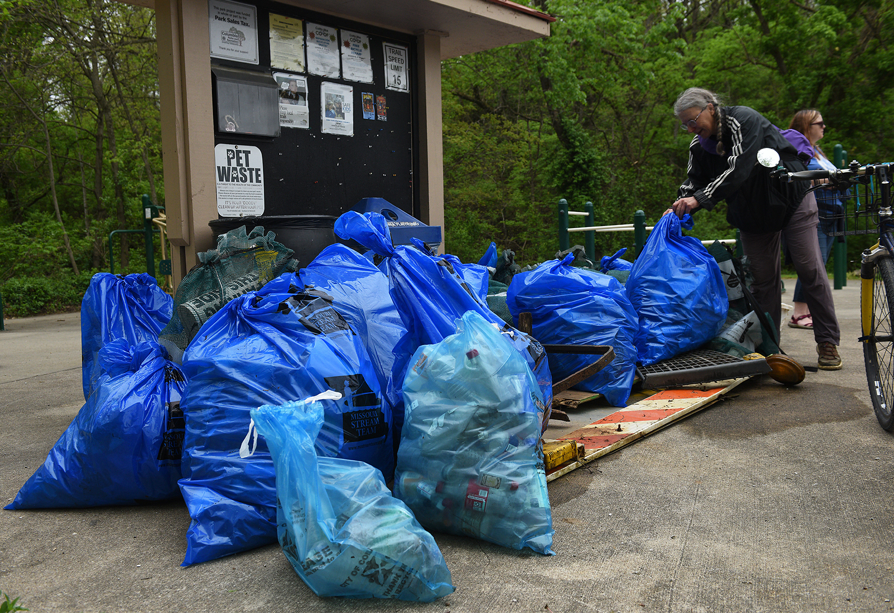 Elke Boyd adds to a collection of garbage bags and other miscellaneous trash waiting to be picked up on Wednesday at the MKT Nature and Fitness Trail in Columbia. Along with smaller trash, larger items such as a “road closed” sign, laundry basket and tire were among the items dug out from the waters.