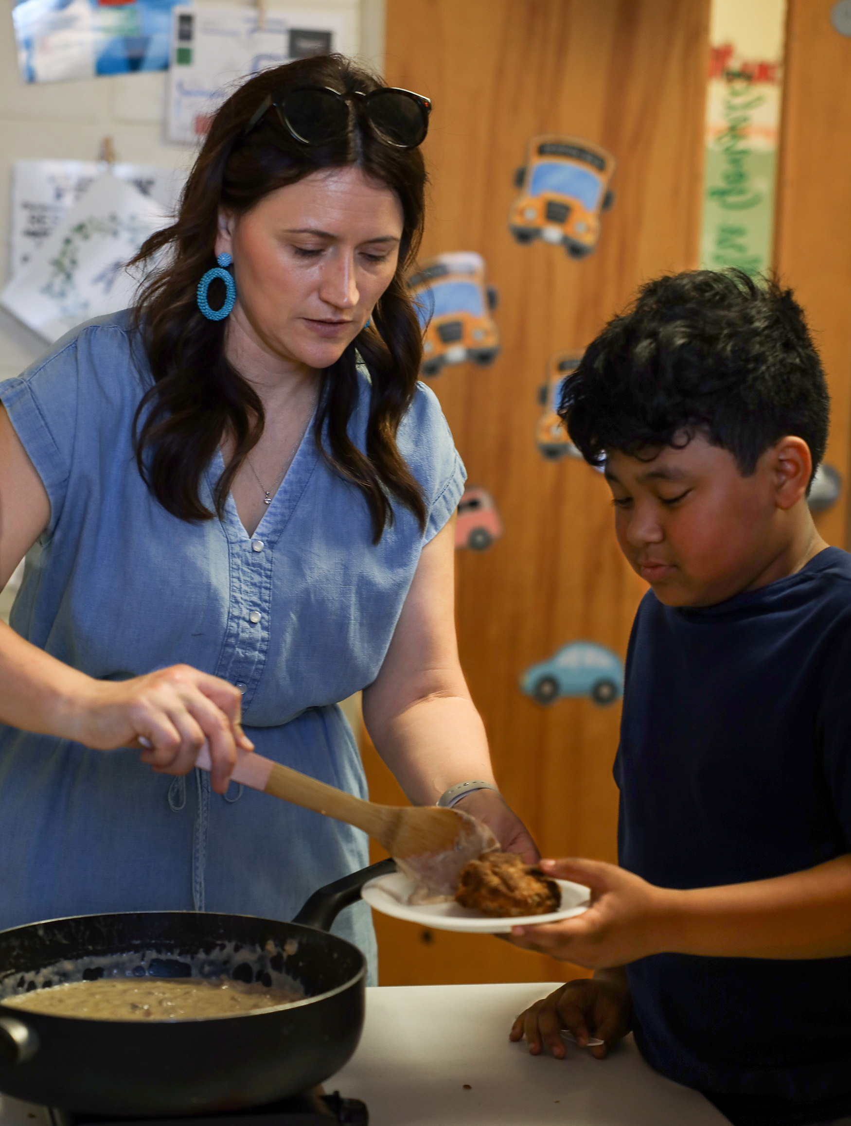 Two Mile Prairie fourth grade teacher Ashley Gonzales serves homemade sausage gravy to Jade Warnke, 9, for the school’s hootenanny event. The school’s hootenanny invites families of students to try their homemade food and see a line-dancing performance by students.