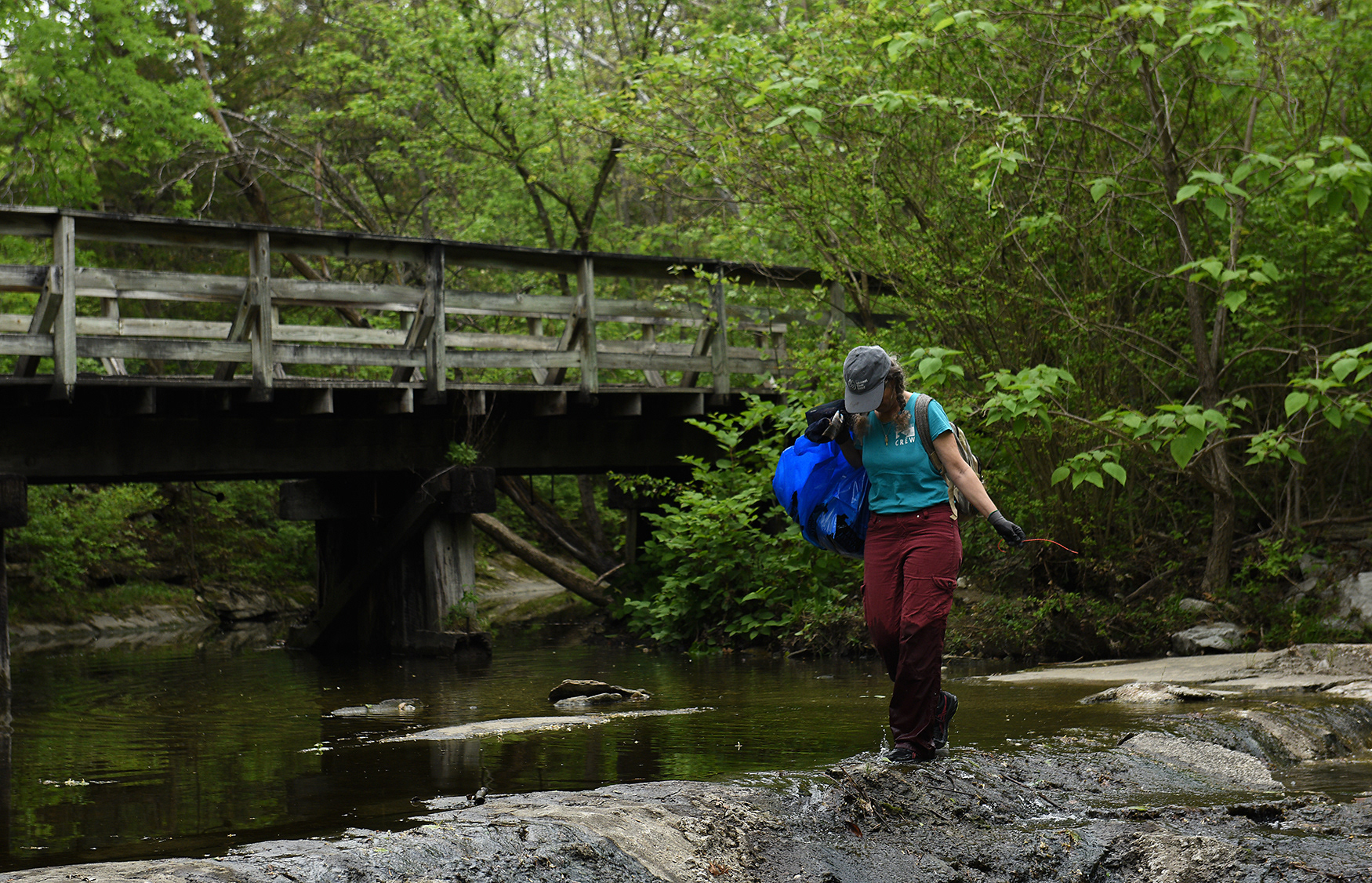 Laura Semken crosses Flat Branch Creek with a bag of trash Wednesday at the MKT Nature and Fitness Trail in Columbia. Semken spent nearly two hours in the water, removing multiple bags worth of waste from the water and nearby land. She was one of over 40 volunteers at the Earth Day cleanup. Event participants were spread out over eight sites around town.