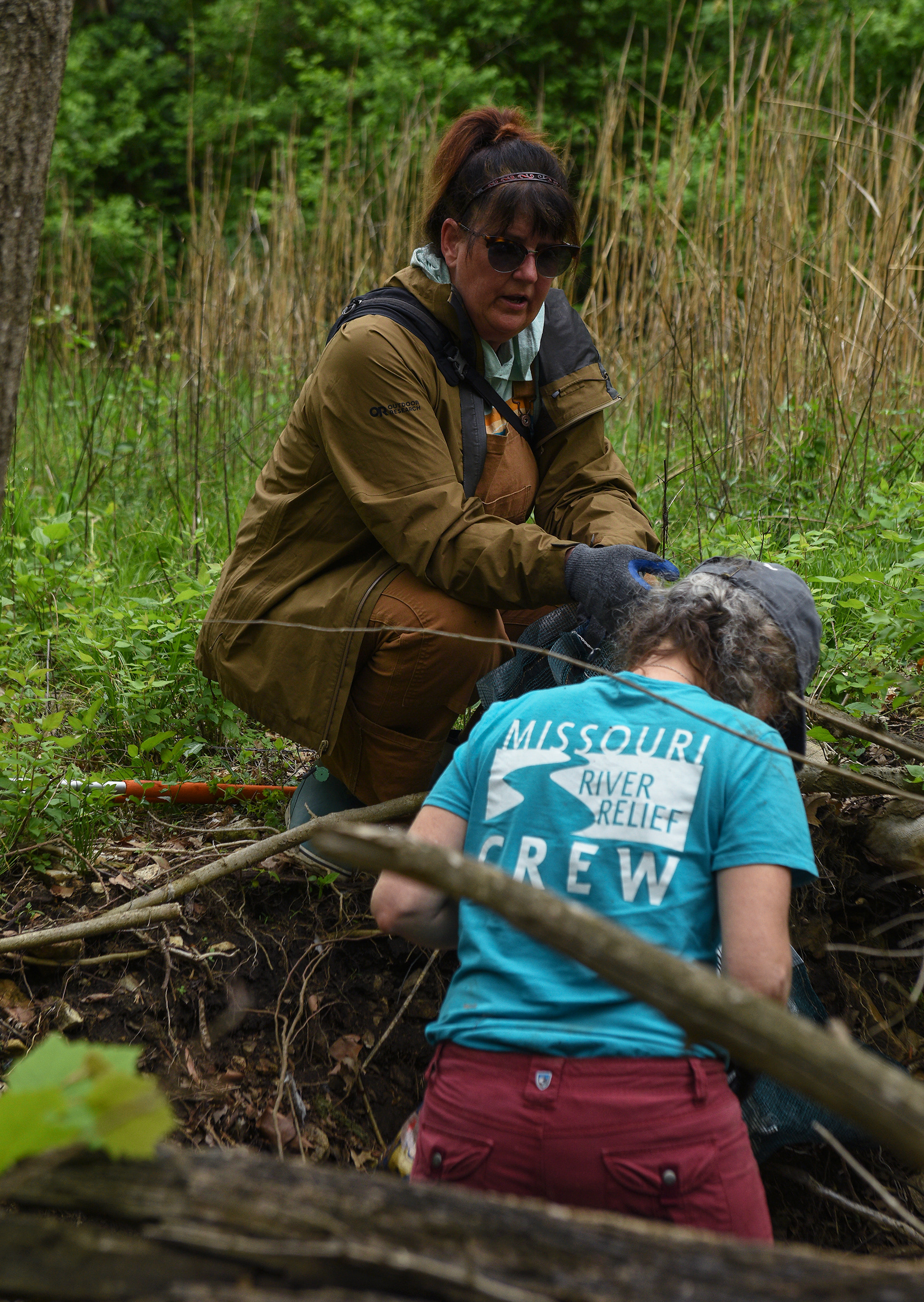 Missouri River Relief Executive Director Jami Wade, left, speaks with crew member Laura Semken, right, while taking a break from picking up waste Wednesday at the MKT Nature and Fitness Trail in Columbia. Wade was hired as executive director in September 2024. She has experience in both business and teaching.