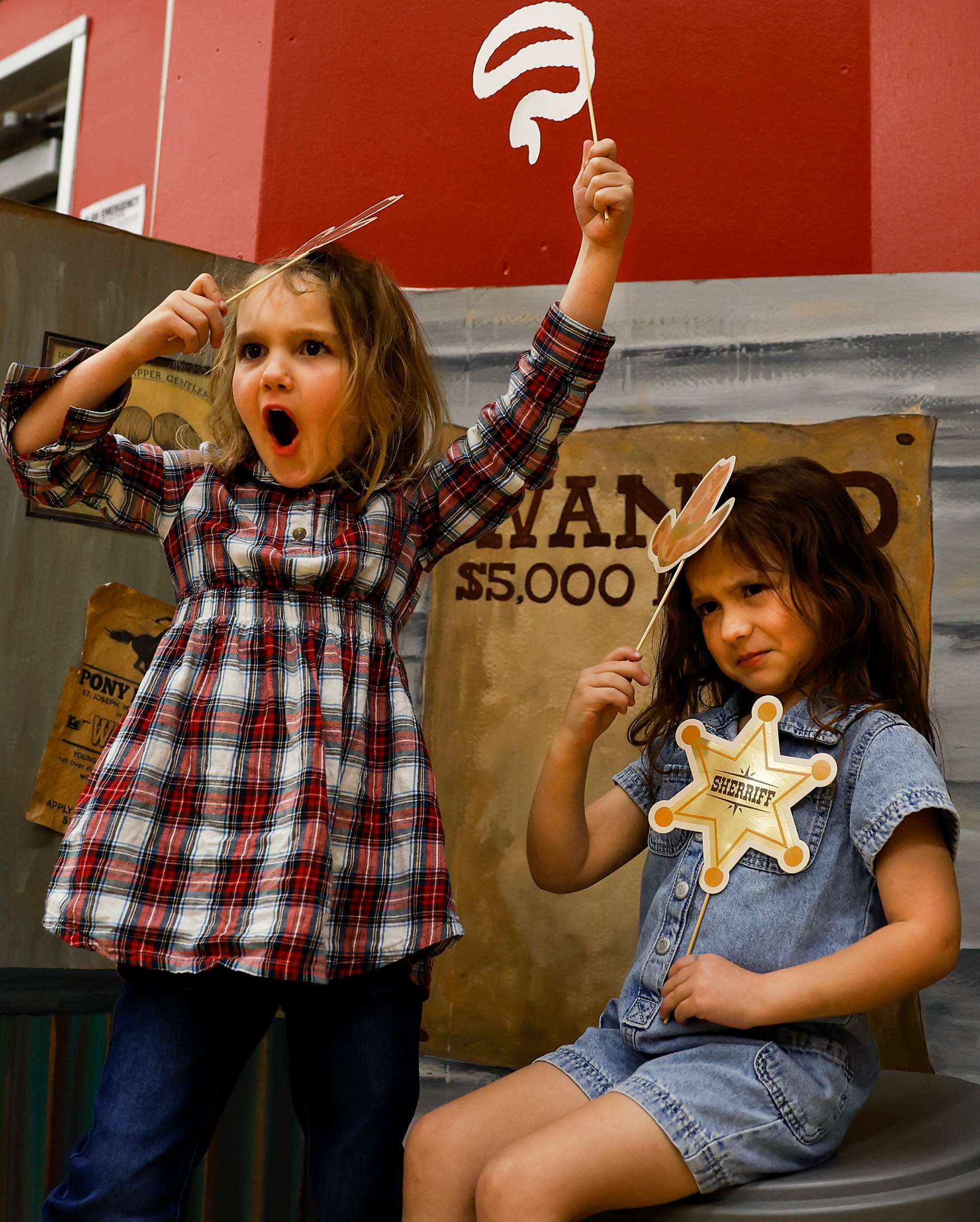 From left, Lily Zimmermann, 5, and Elliana Gonzales, 5, pose during the hootenanny on March 19 at Two Mile Prairie Elementary School in Columbia. The hootenanny had a Wild West theme and a matching photo booth in which attendees could take photos with themed accessories.