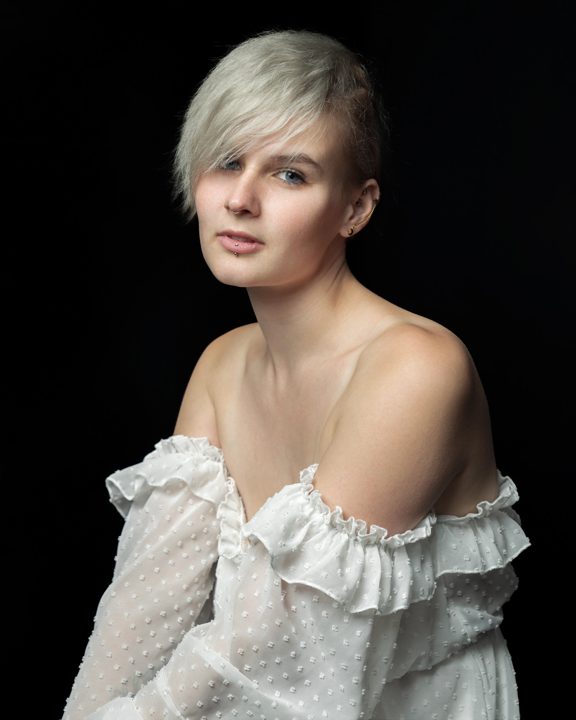 Portrait of model Sisse wearing white off shoulder dress in professional studio setting