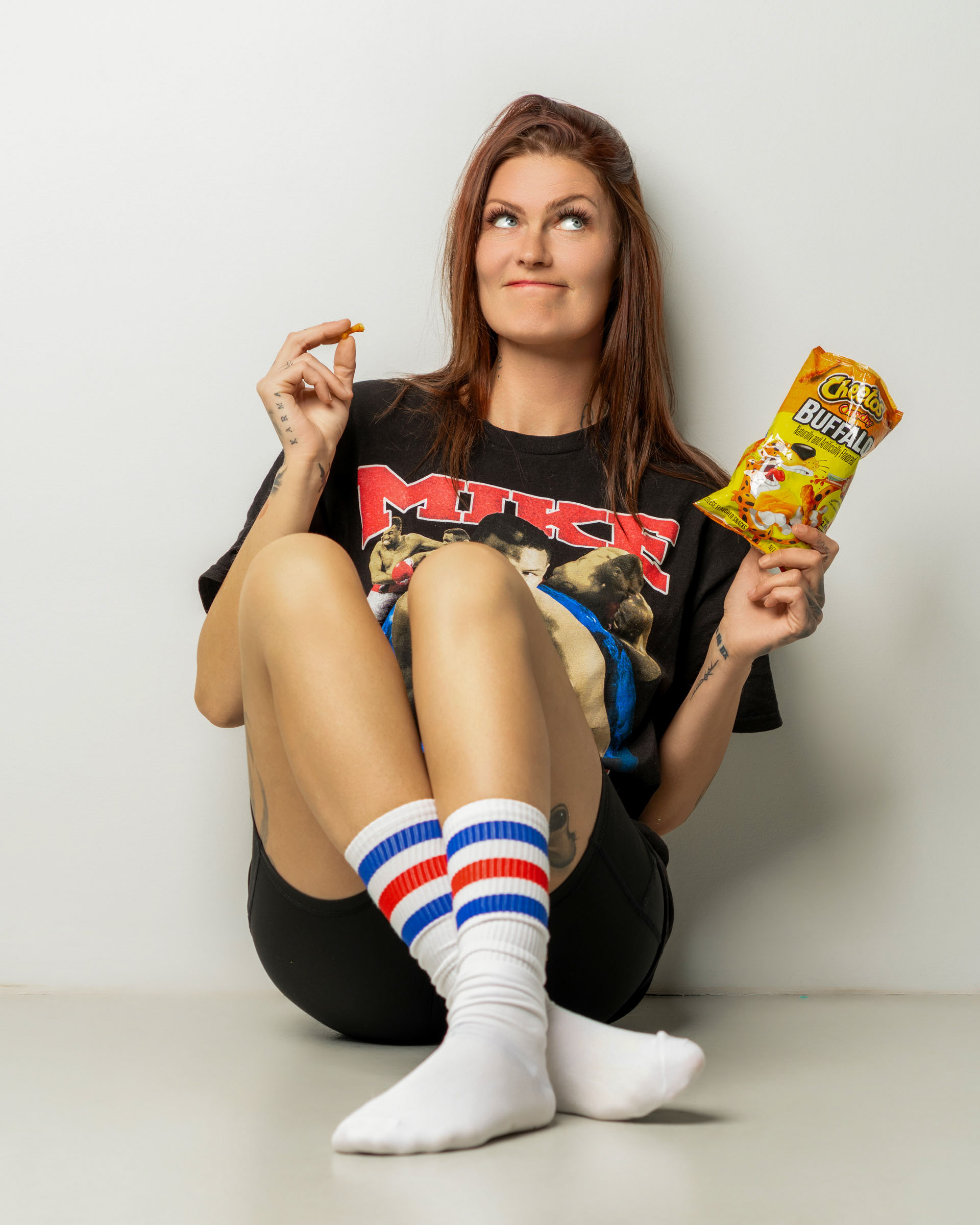 Lifestyle-inspired image of a woman savoring a cheese puff in a clean, minimal studio setting.