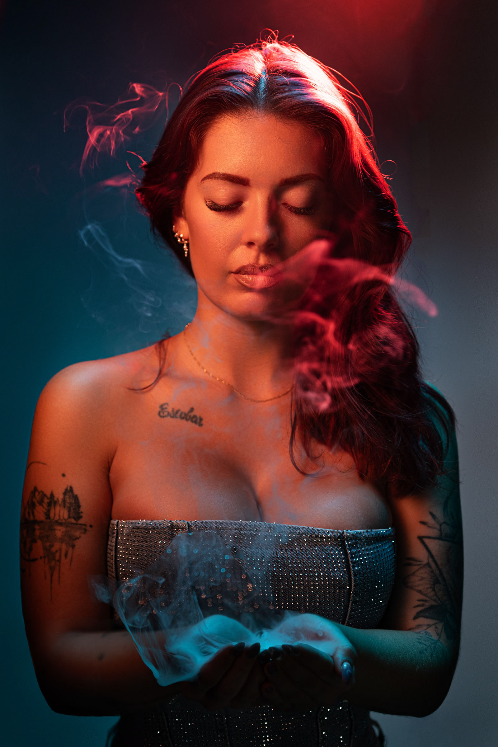 Portrait of a woman in a glittering dress under dramatic colored LED lights, holding vapor in her hands at a creative photo event with Nanlite lighting.