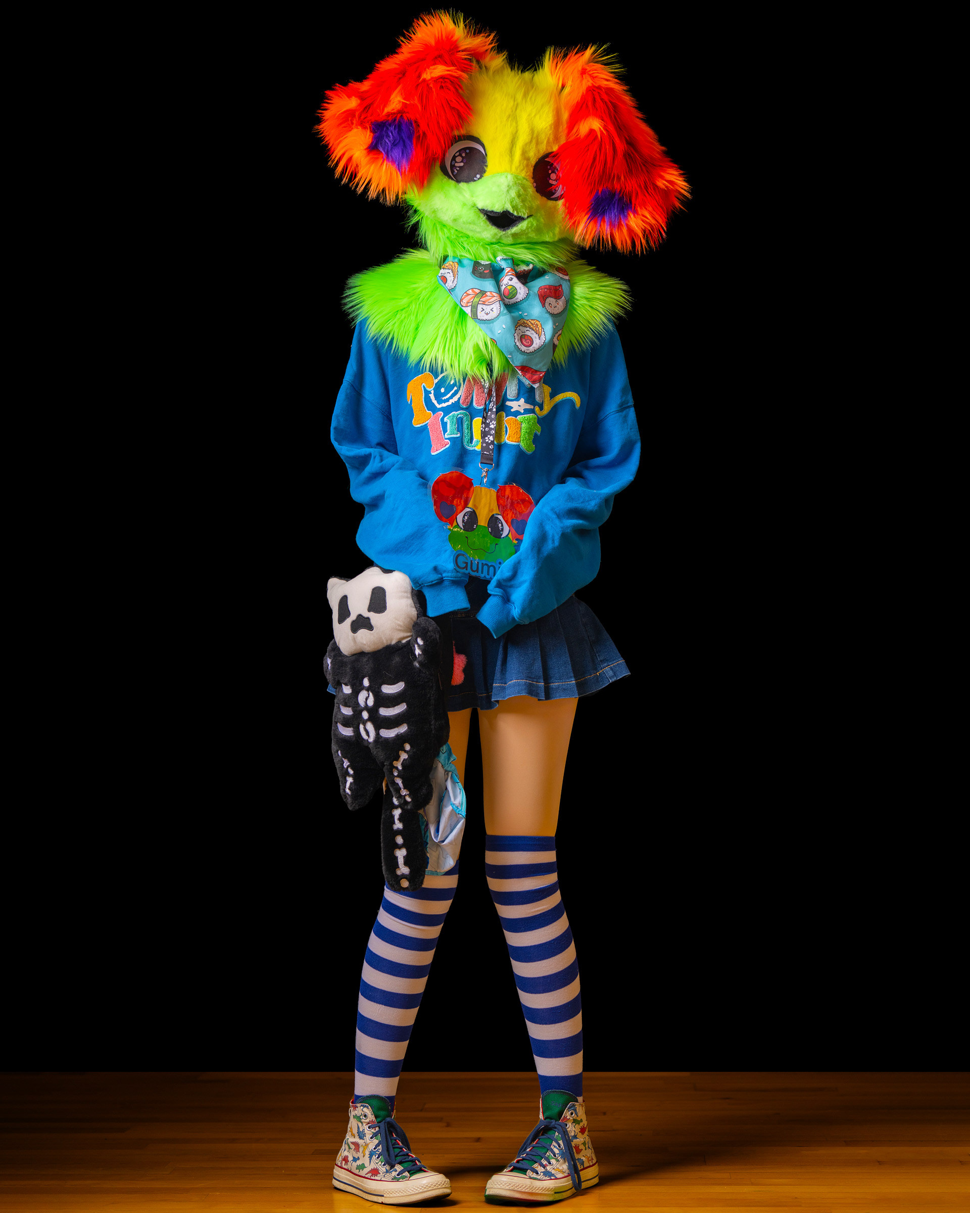 Full body studio photo of fursuit model in striped socks and colorful costume, character themed photoshoot.