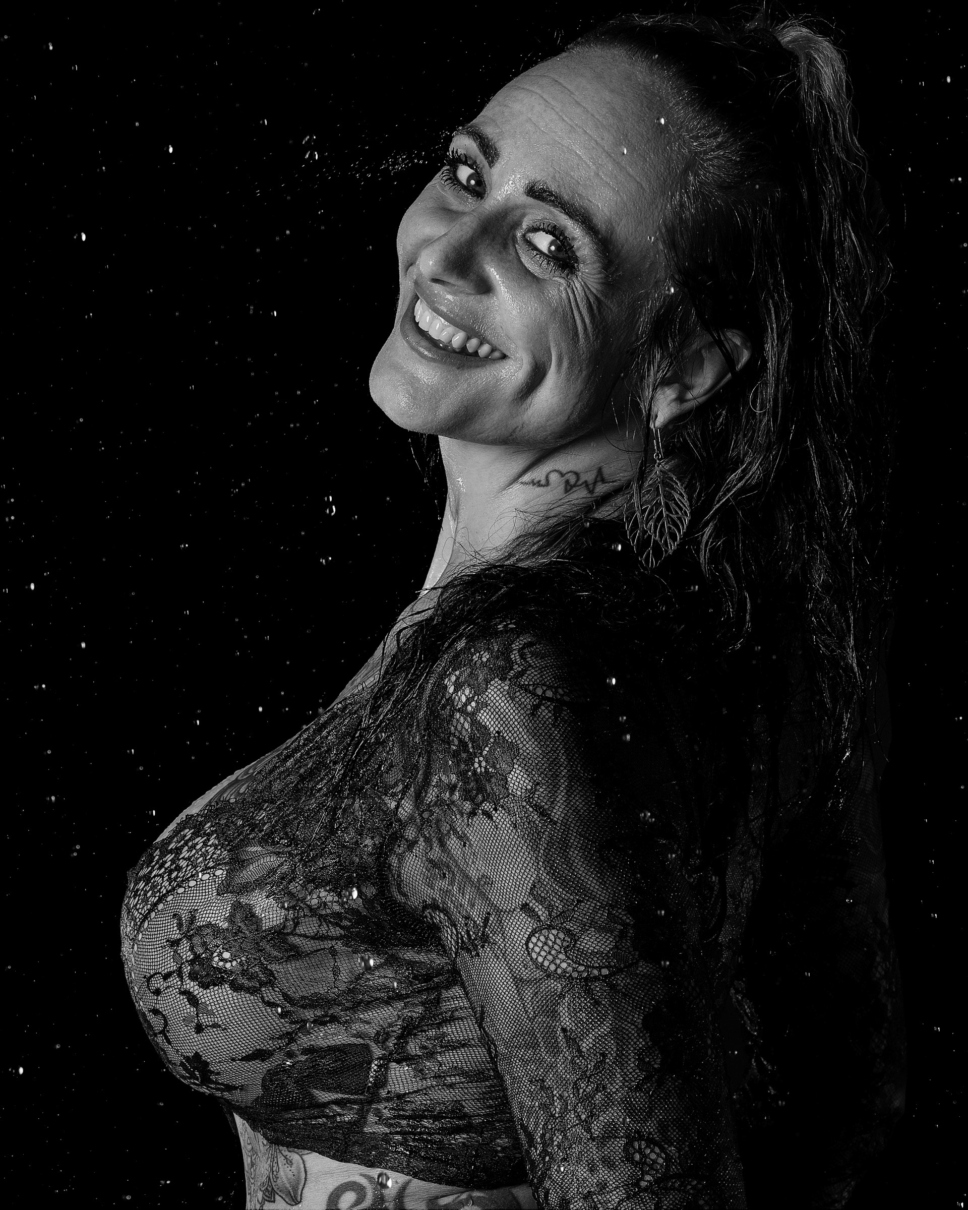 Smiling black and white studio shot of model Terese in wet look lingerie photography
