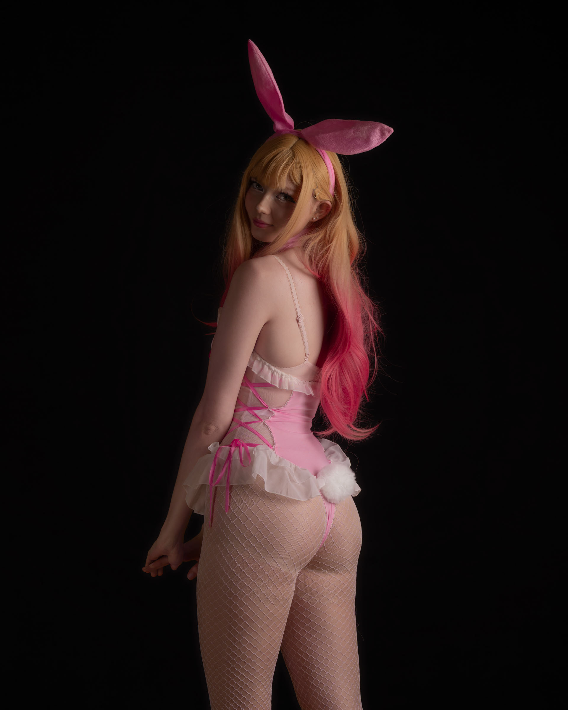 Ninu in pastel bunny bodysuit showing soft pose and warm studio lighting.