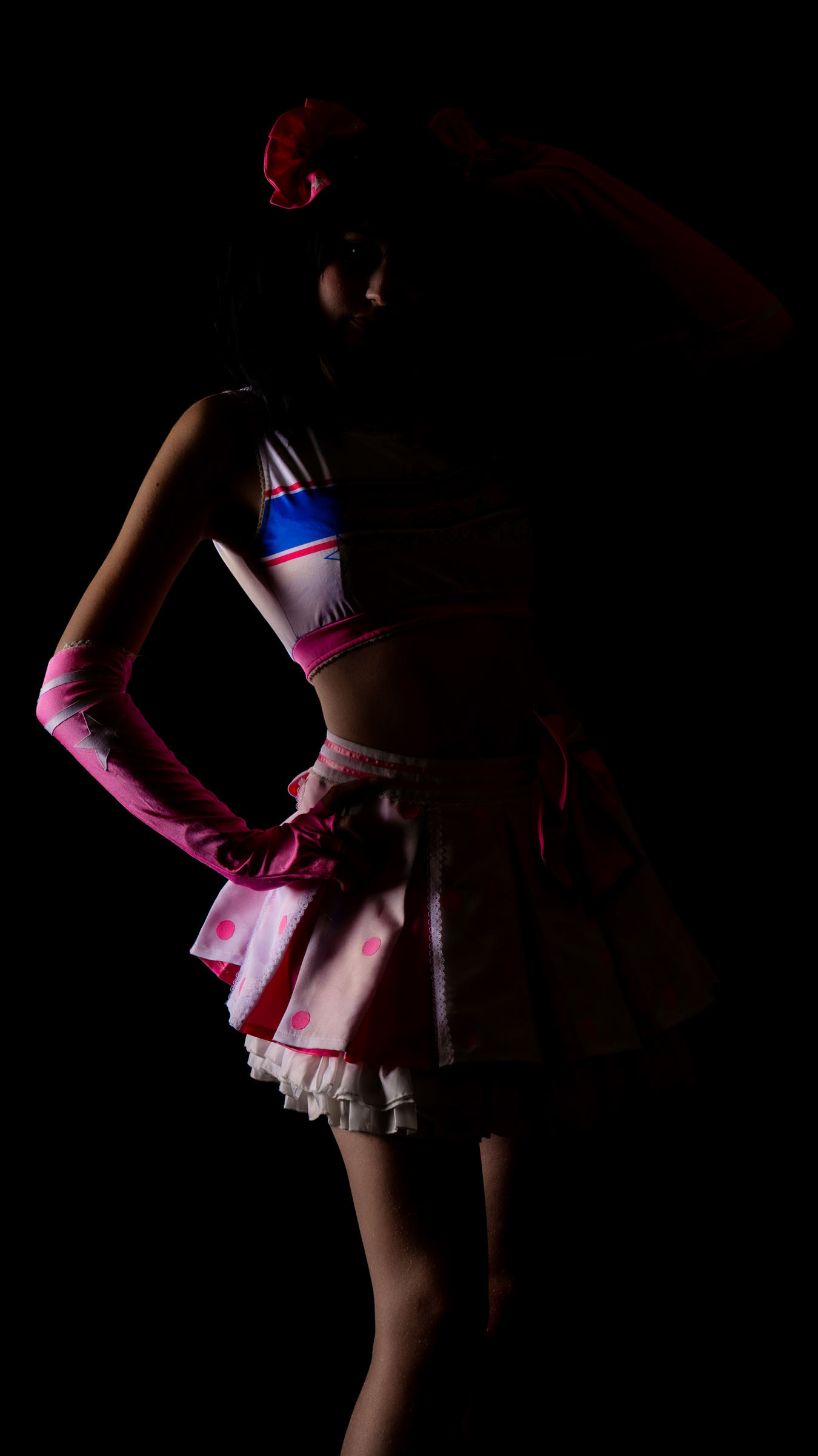 Silhouette photo of cosplayer may_c0z dressed as Nico Yazawa from Love Live, lit with dramatic low light emphasizing the pink idol outfit.
