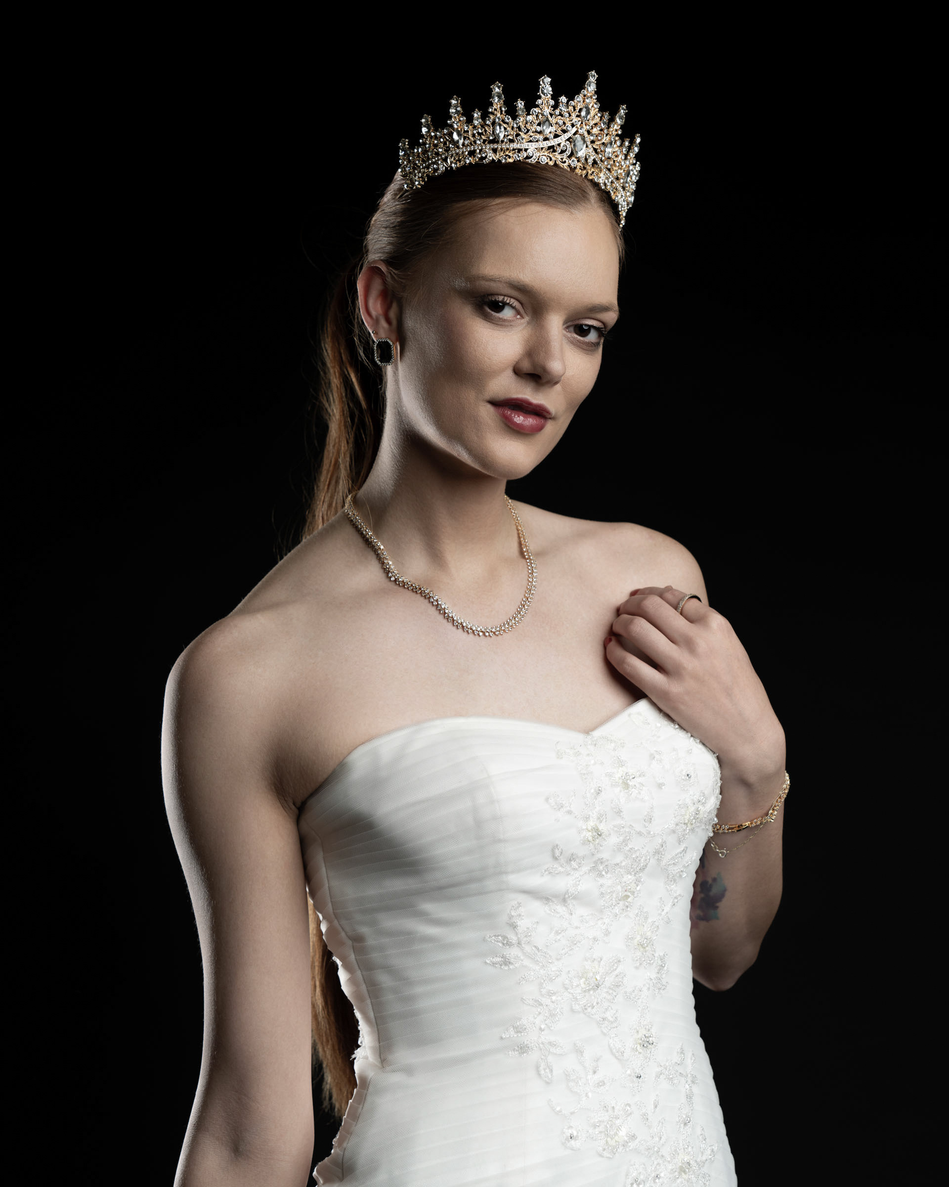 Close-up portrait of Noamynte with a golden crown and bridal gown, looking directly into the camera.