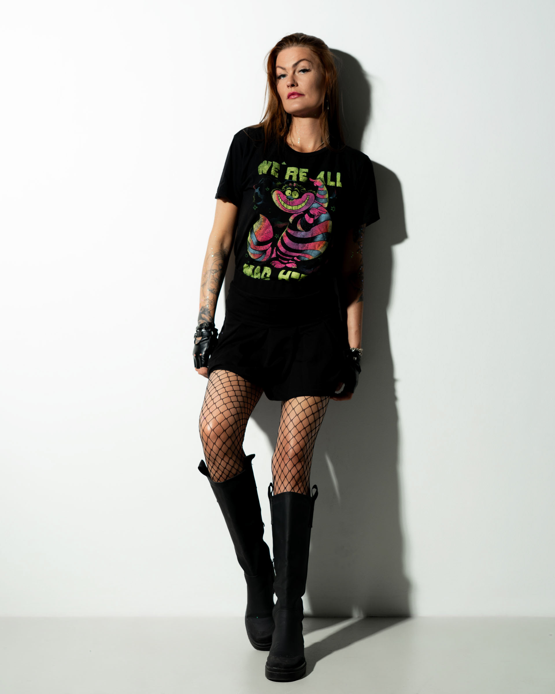 Simone standing relaxed against a white background, her shadow clearly defined behind her as she poses casually.