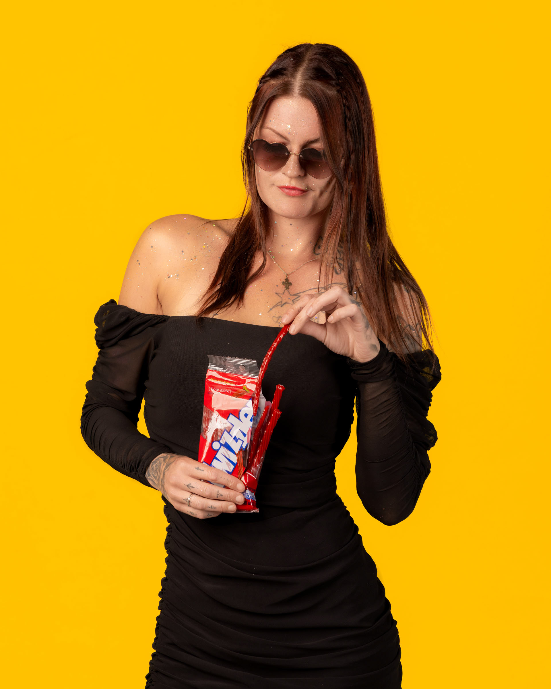 Vibrant studio image of a model enjoying red licorice candy during a playful, sweet-themed photoshoot.