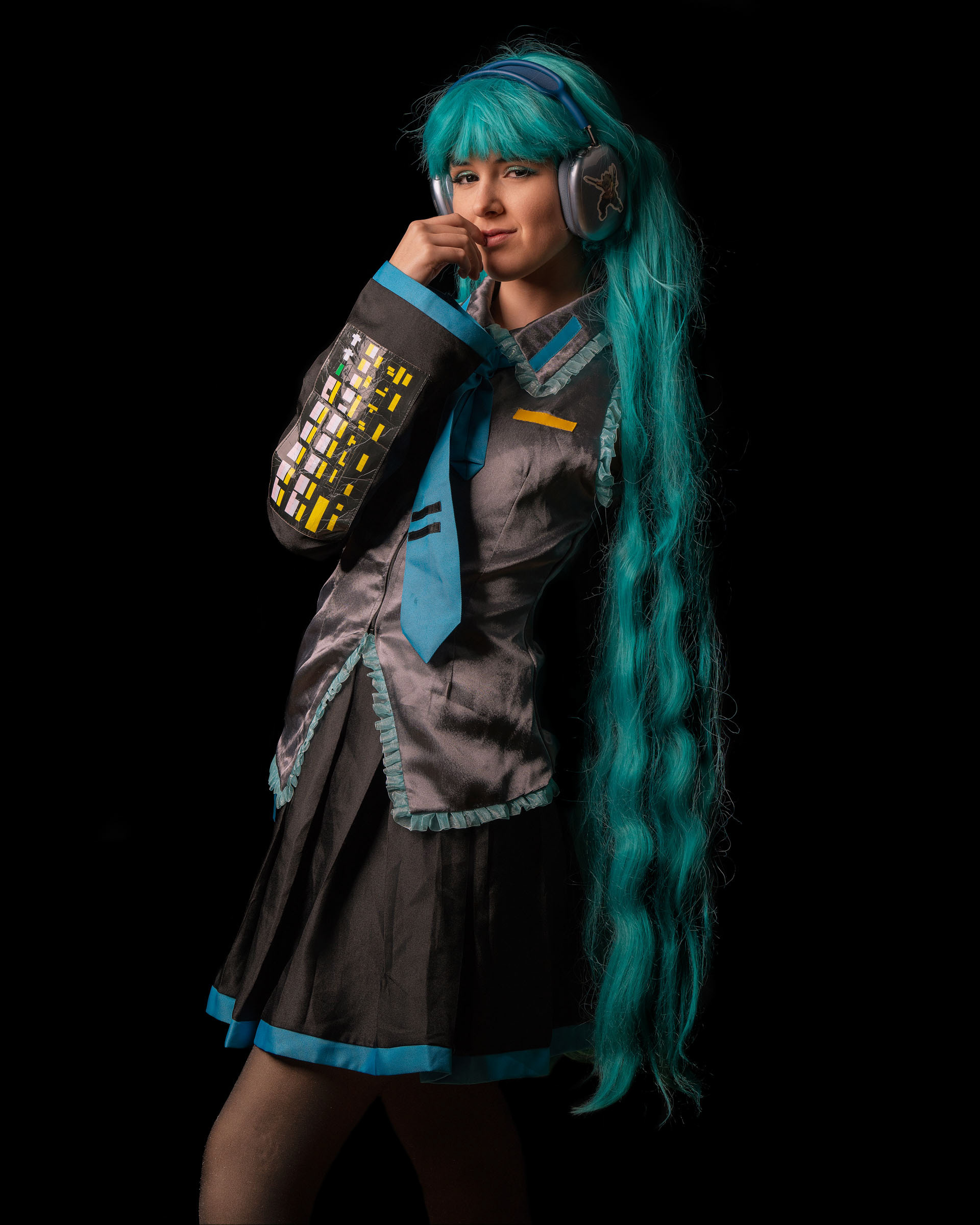 Another variant of a thoughtful pose from a Hatsune Miku cosplayer, showcasing long turquoise hair and character accuracy.