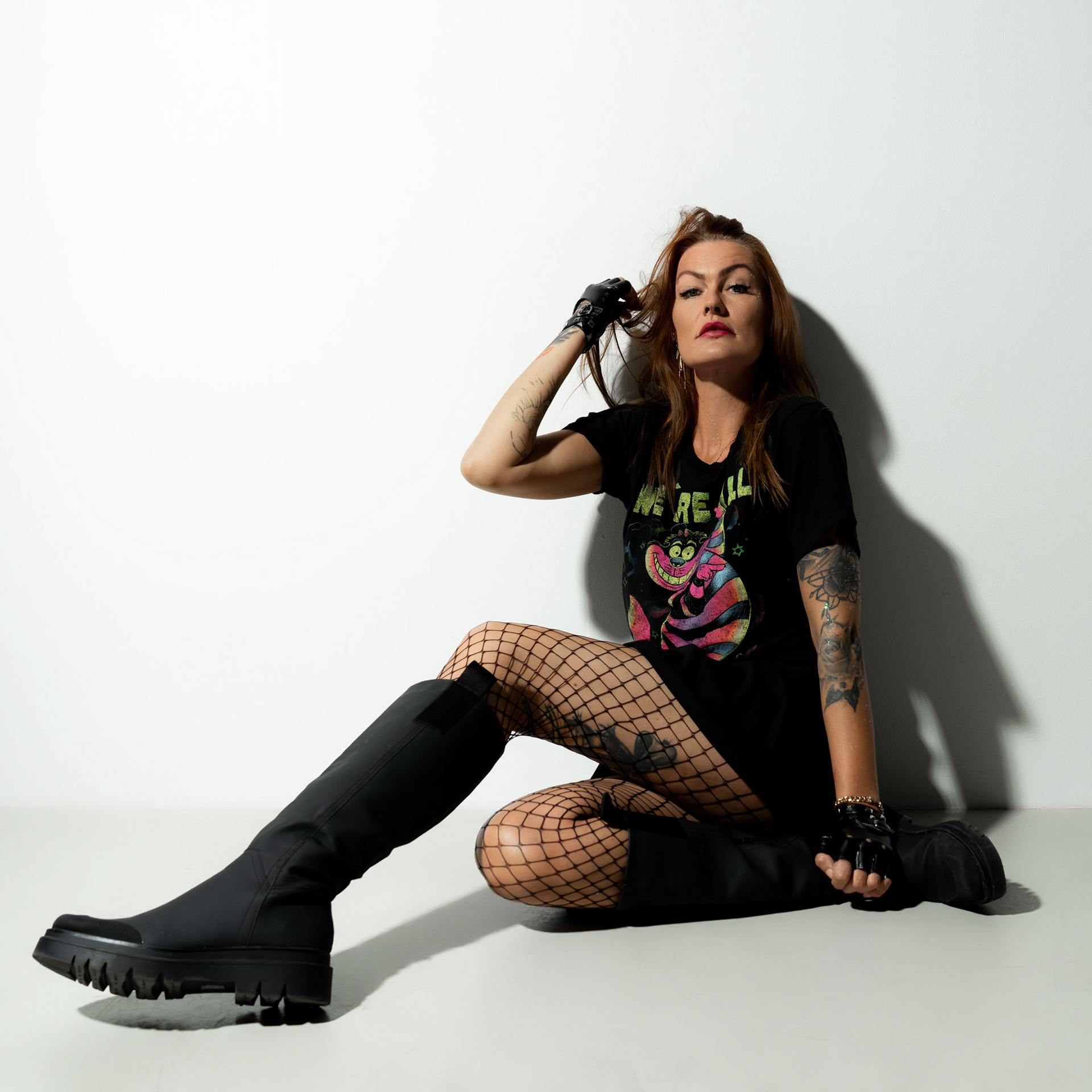 Simone adjusting her hair while sitting on the floor, looking confidently at the camera with an expressive pose.