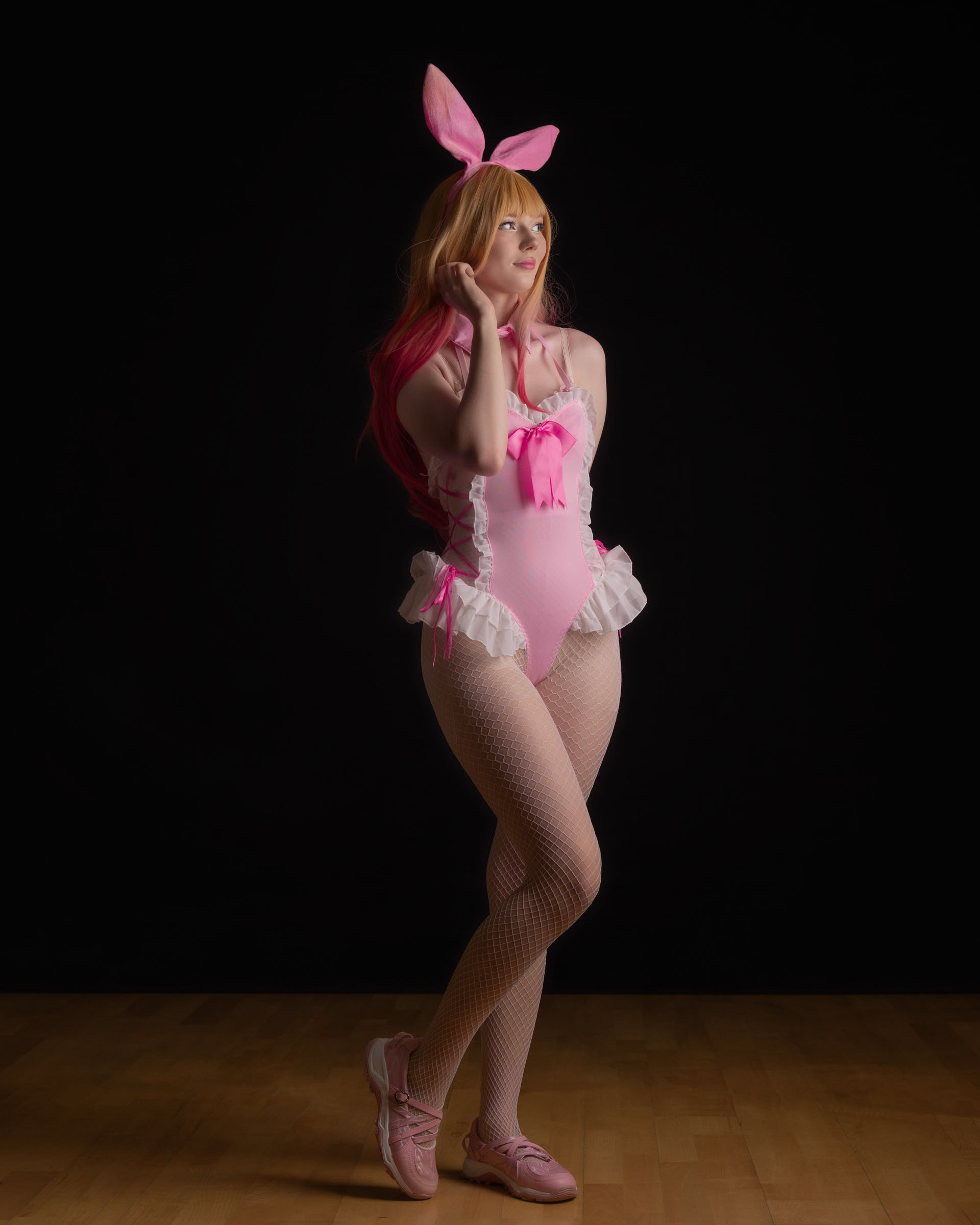 Full-body shot of Ninu in pink bunny cosplay, playful stance and pastel aesthetic.