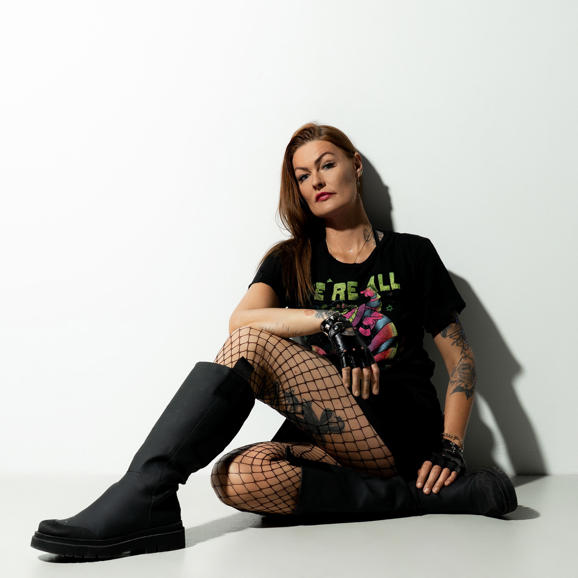 Simone sitting on the floor against a white backdrop, looking directly at the camera with a calm, confident expression.