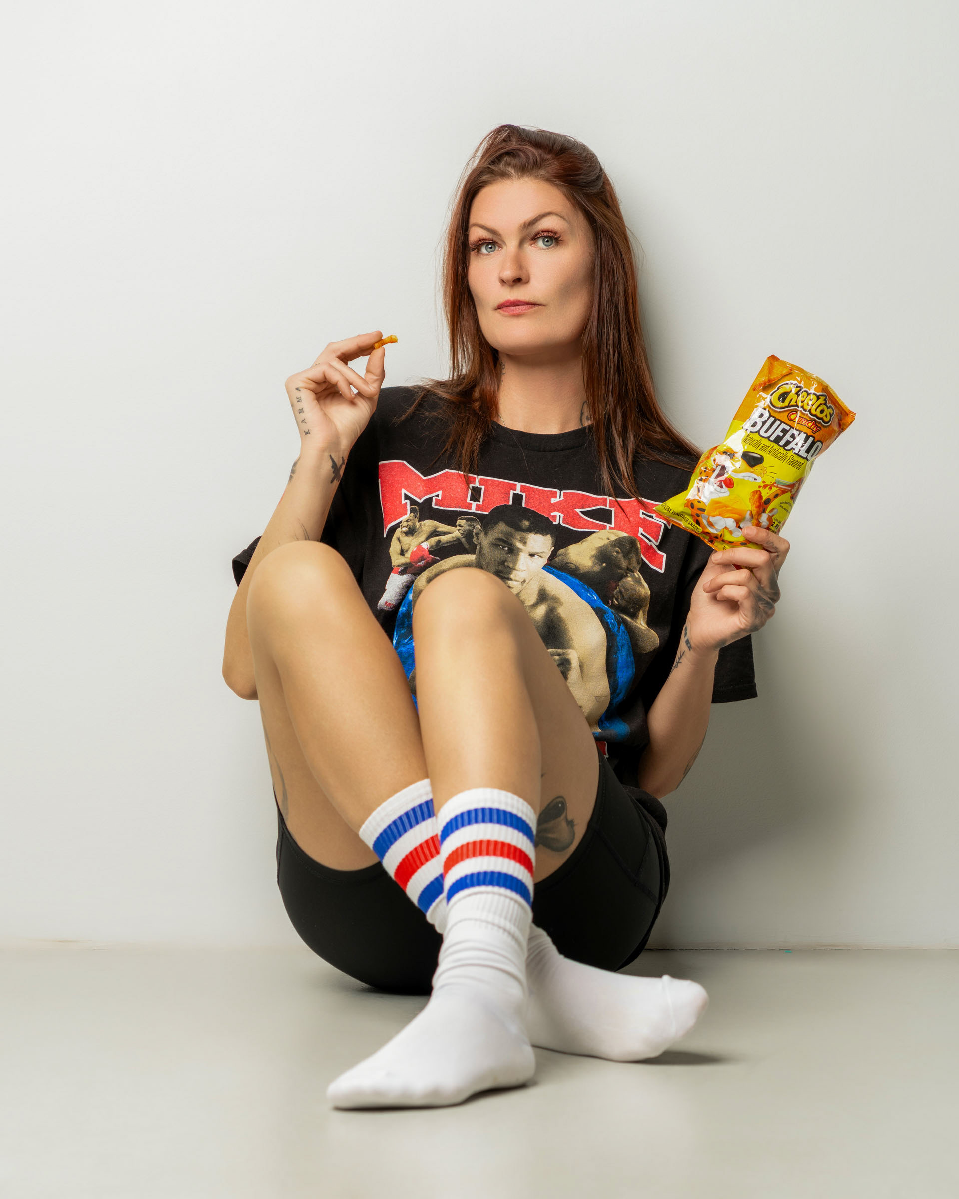 Casual snack-themed portrait of a woman holding Cheetos while dressed in a vintage-style graphic shirt.
