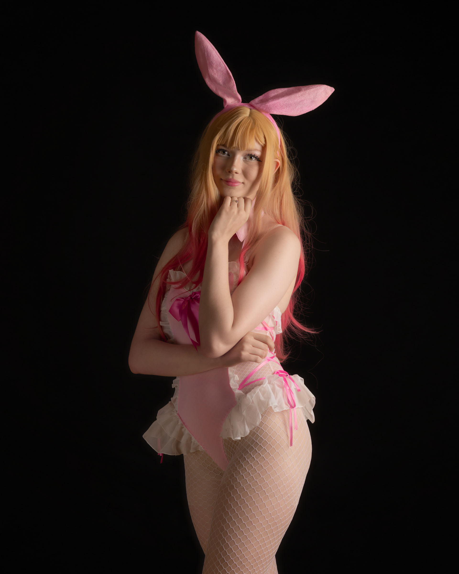 Ninu in pink bunny outfit looking thoughtful and playful, ruffled details and soft pastel styling.