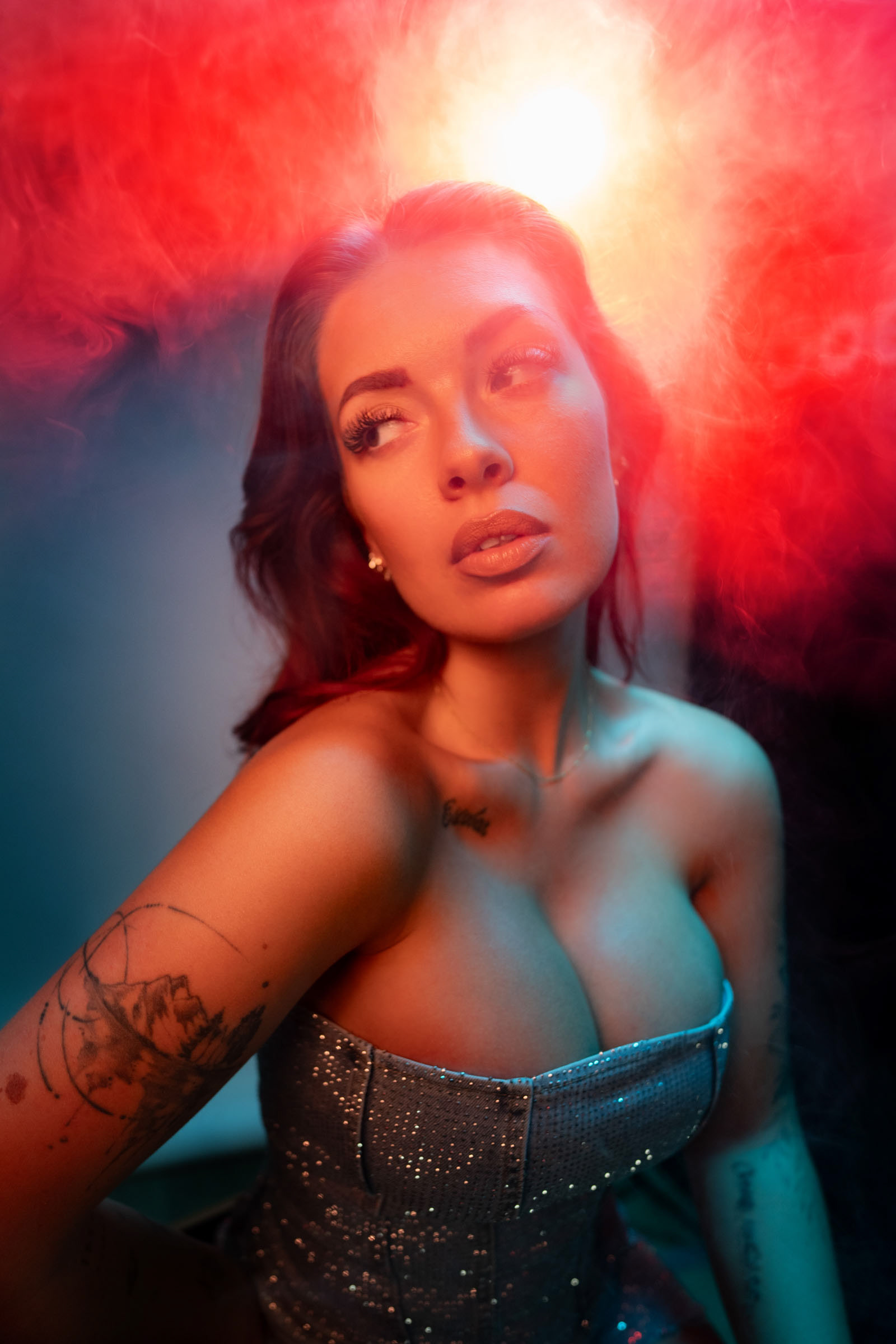 Female model with closed eyes holding smoke, lit by red and blue Nanlite LED lights during a Goecker x Sony photography workshop in Copenhagen.