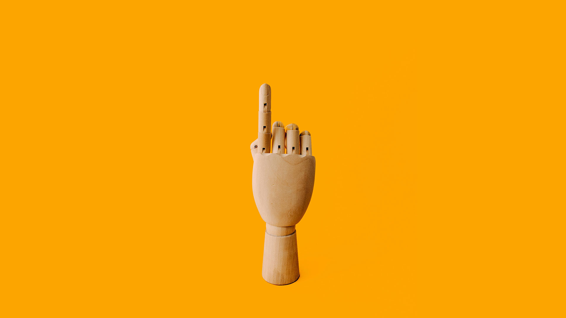 Vibrant orange background, wooden right hand with pointed finger pointing up.