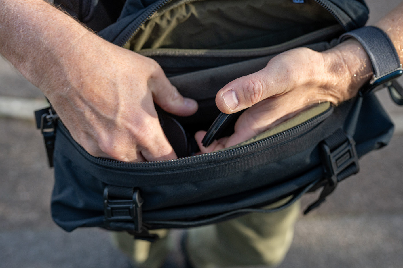 Pulling a lens cap from the crossbody camera bag