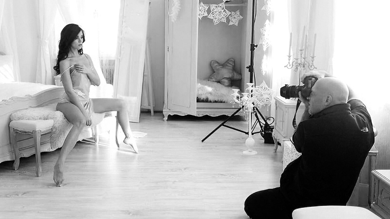 Photographer LeFu at work in a studio setting, shooting a model in lingerie. Behind the scenes of an indoor fashion and lingerie shoot.