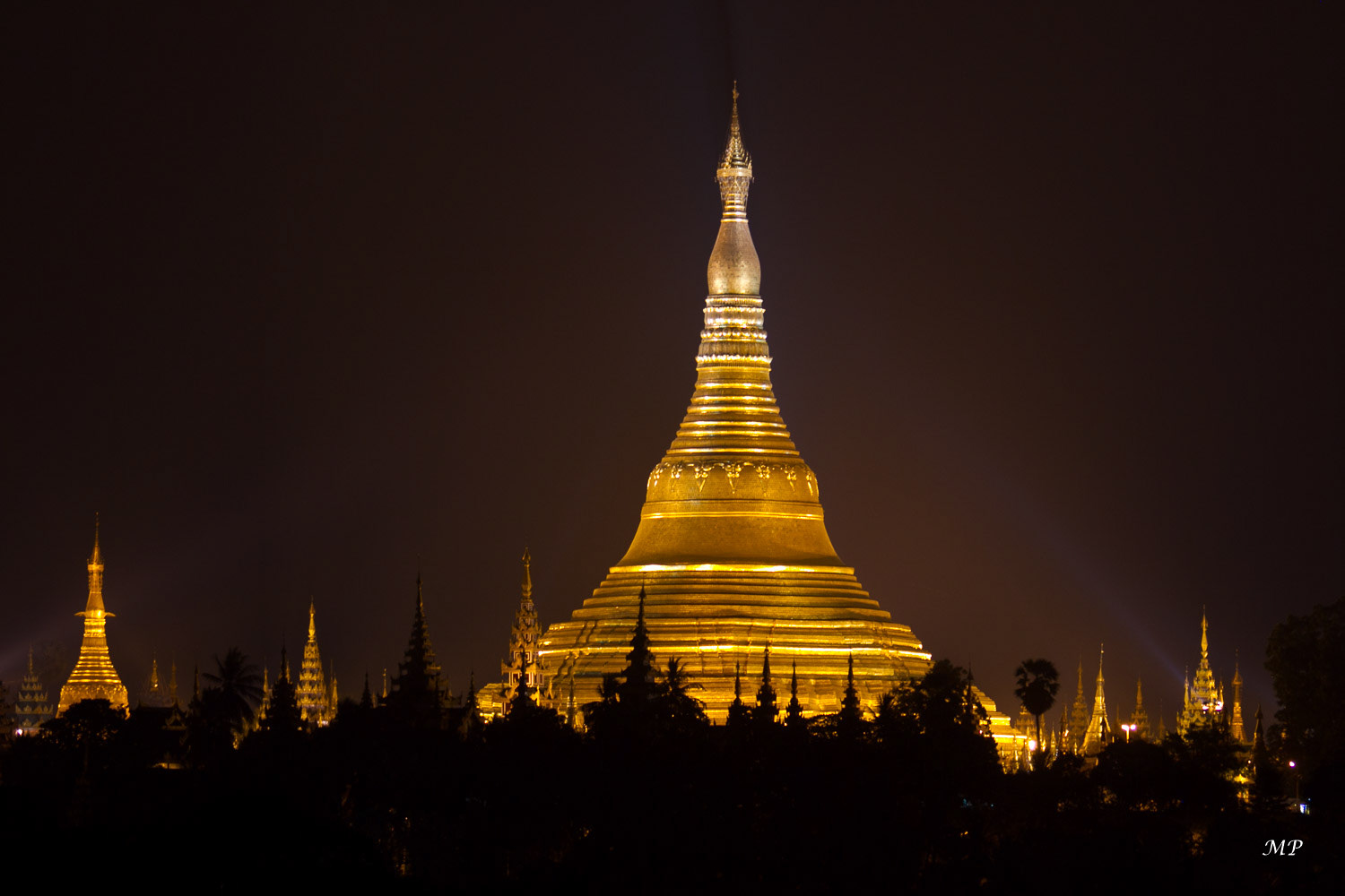 Yangon: Eblouissante de jour comme de nuit, la pagode de Shwedagon brille de mille feux. Elle est pour les bouddhistes birmans le sanctuaire le plus sacré du pays. L'imposant dôme doré s'élève à 98m au-dessus de sa base. La légende fait remonter la fondation de ce stupa à deux millénaires et demi mais les archéologues estiment qu'il date d'une période entre le VIème et Xème siècle (époque Môn). Il fut souvent rebâti à la suite de tremblements de terre; la construction actuelle date de 1769.