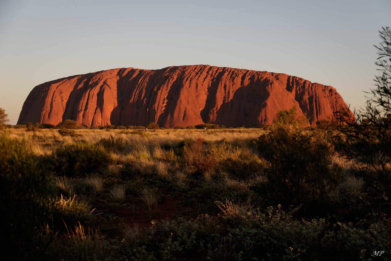 Suivant l'heure de la journée, les couleurs  d’Uluru varient du rose au rouge foncé en passant par le pourpre, sous un ciel toujours rayonnant. Ici au coucher du soleil.