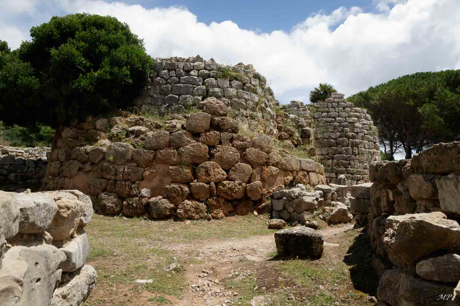 Nuraghe Palmavera - Un nuraghe est un édifice mégalithique  caractéristique de la culture nuragique apparue en Sardaigne entre 1900 et 730 av. JC. Celui de Palmavera est situé à 8km d'Alghero. La Tour est entourée des vestiges d'une cinquantaine de maisons dont une salle circulaire encore équipée de son banc circulaire.