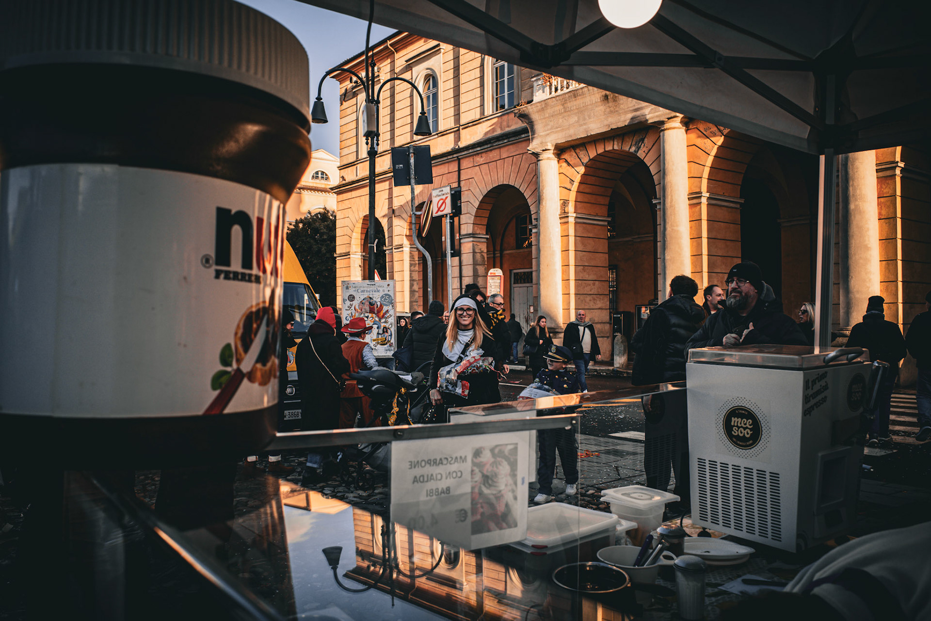 Between glass reflections and ancient architecture, the celebration drifts toward evening. Sweets remain guarding the counter, while faces smile, tired and still dusted with confetti. The city catches its breath but holds on to something: a sweet taste, a warm light, a memory that walks slowly.