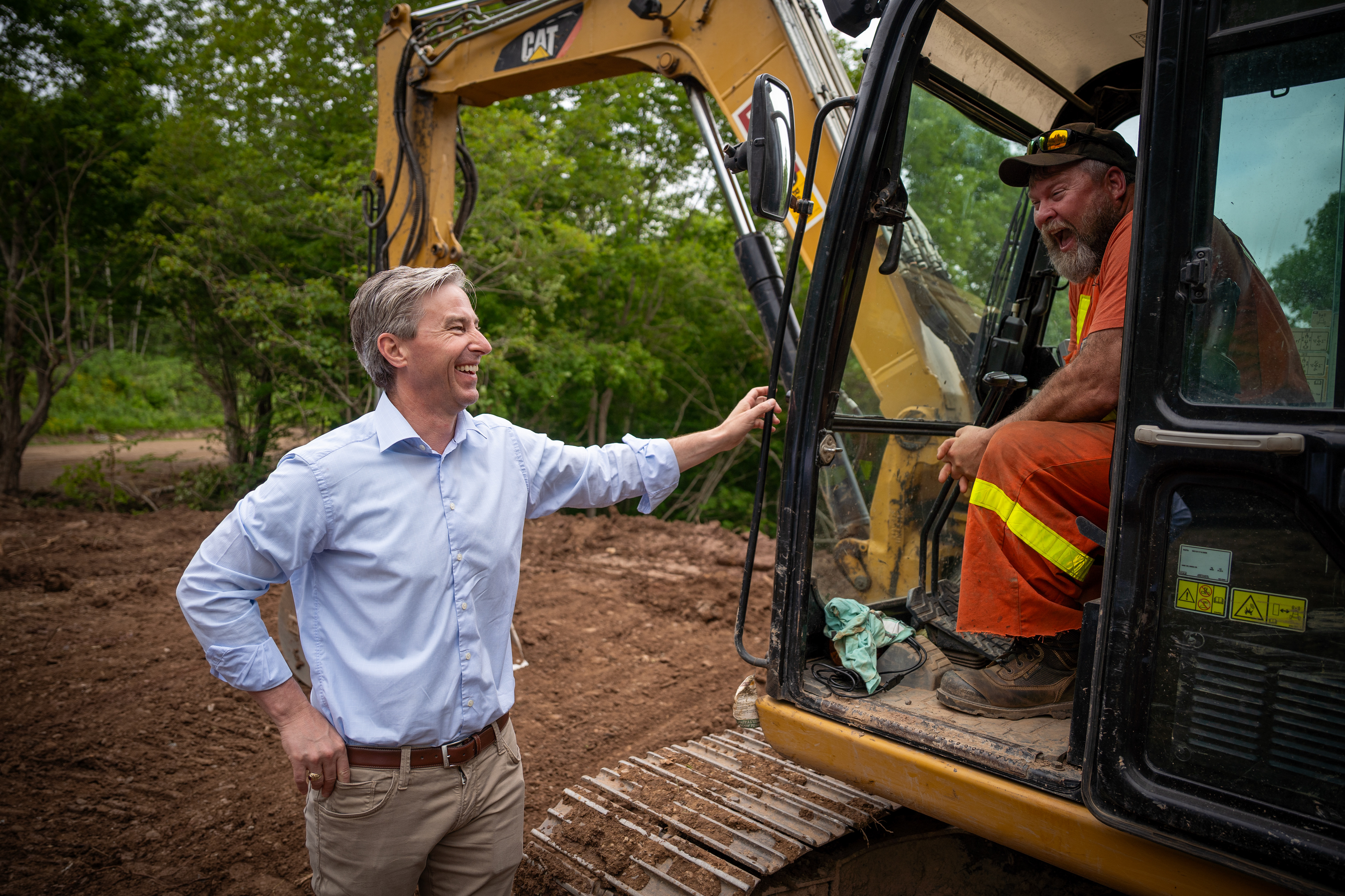 Premier Tim Houston and a construction worker share a laugh on Cape Breton Island, Nova Scotia. June 30, 2023.