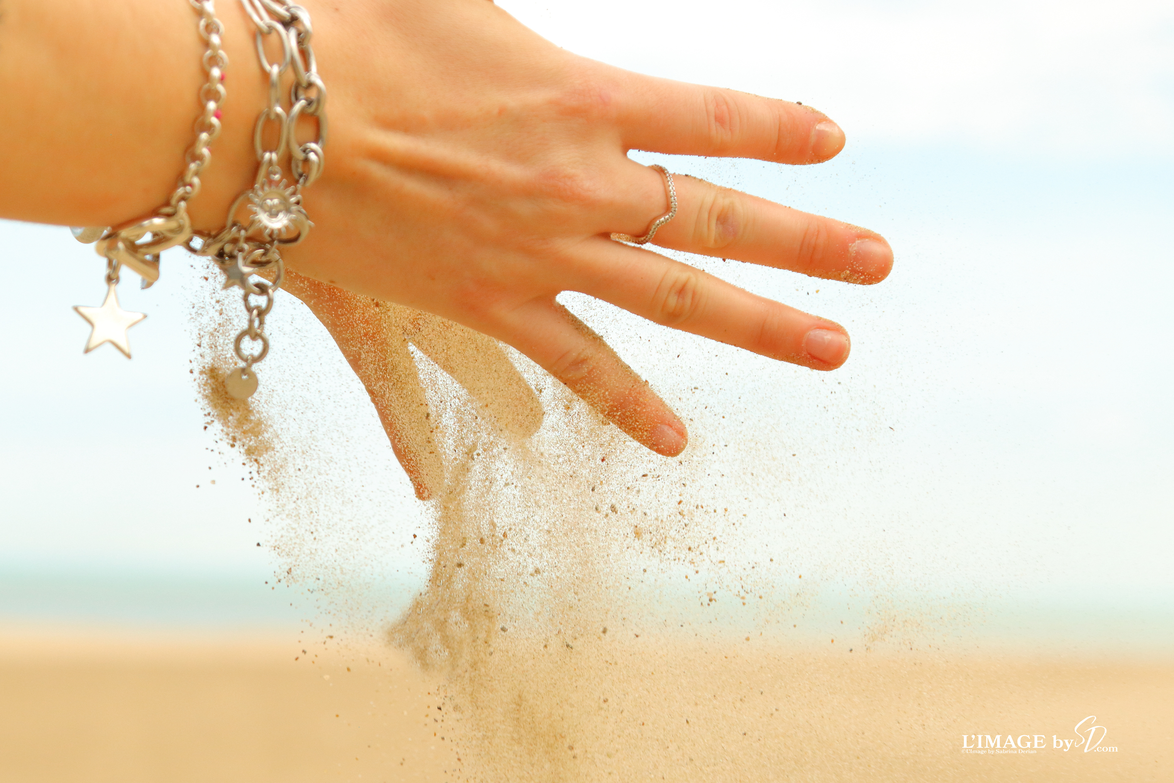 hands releasing sand at beach