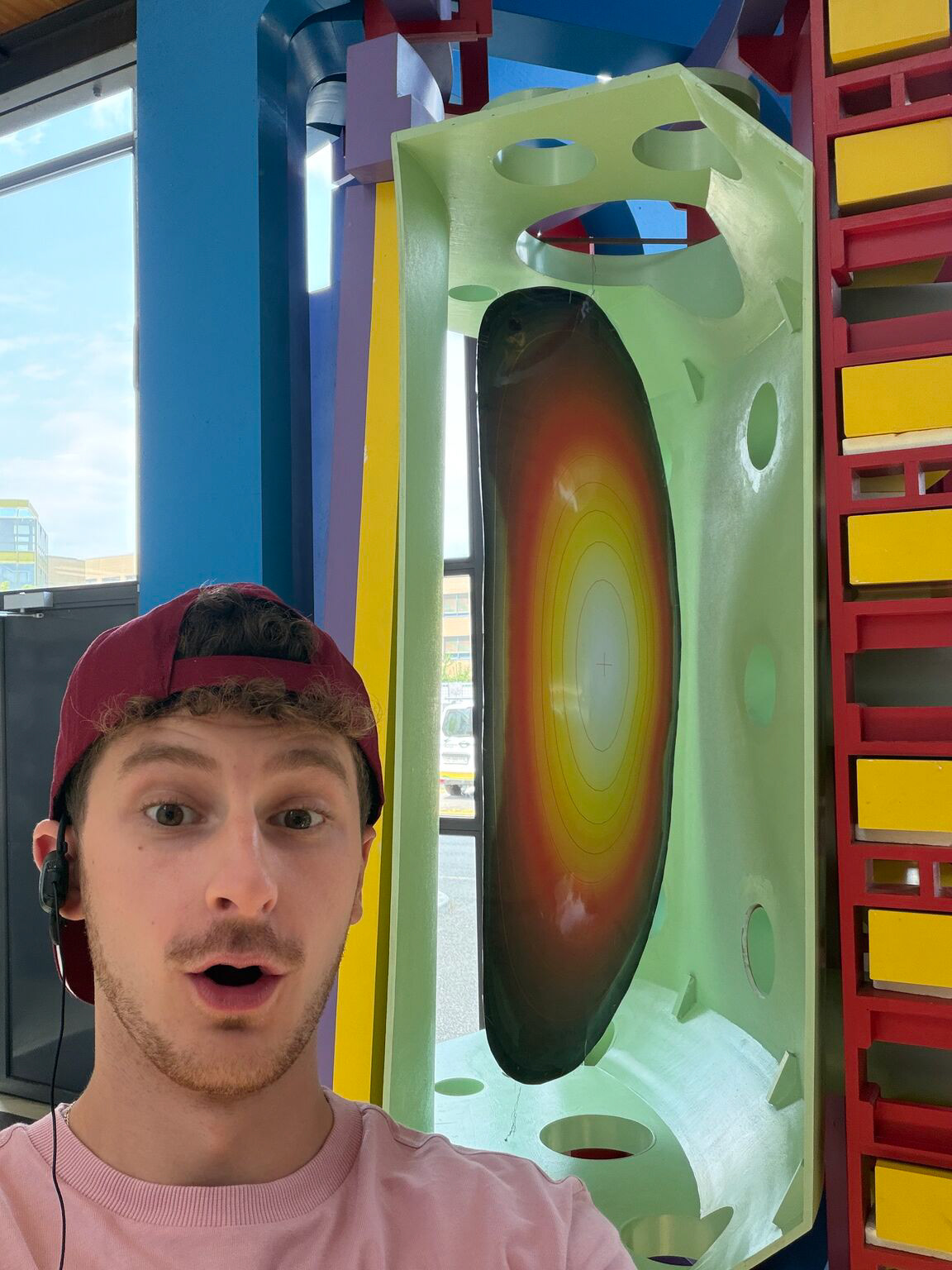 Becker taking a selfie beside a cross-section model of a tokamak at EPFL