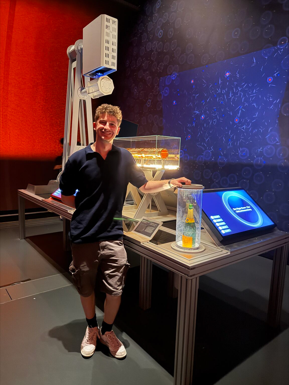 Becker standing beside an illuminated exhibit at CERN in Geneva