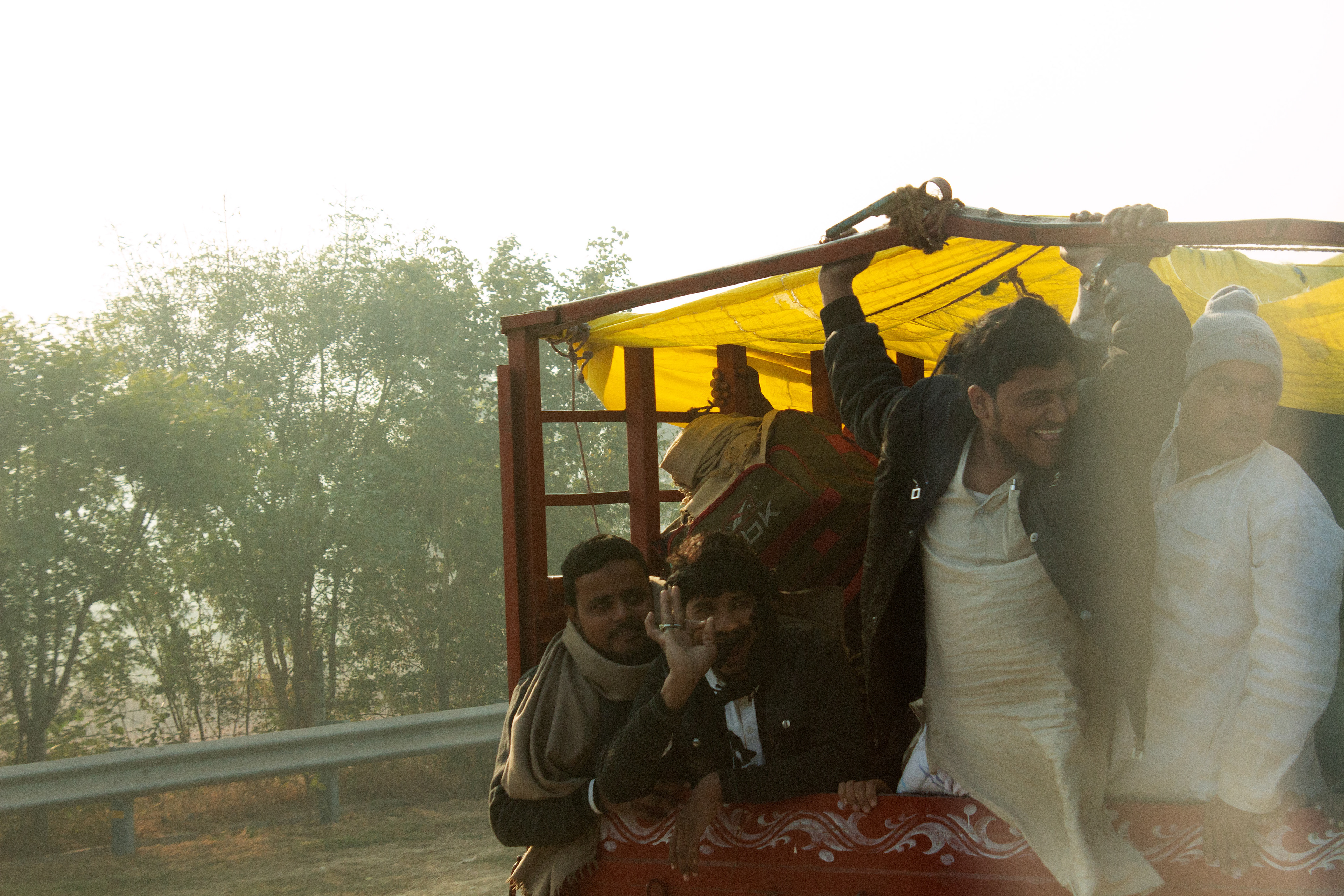 Men in the back of a truck on the freeway, on the road to Agra.