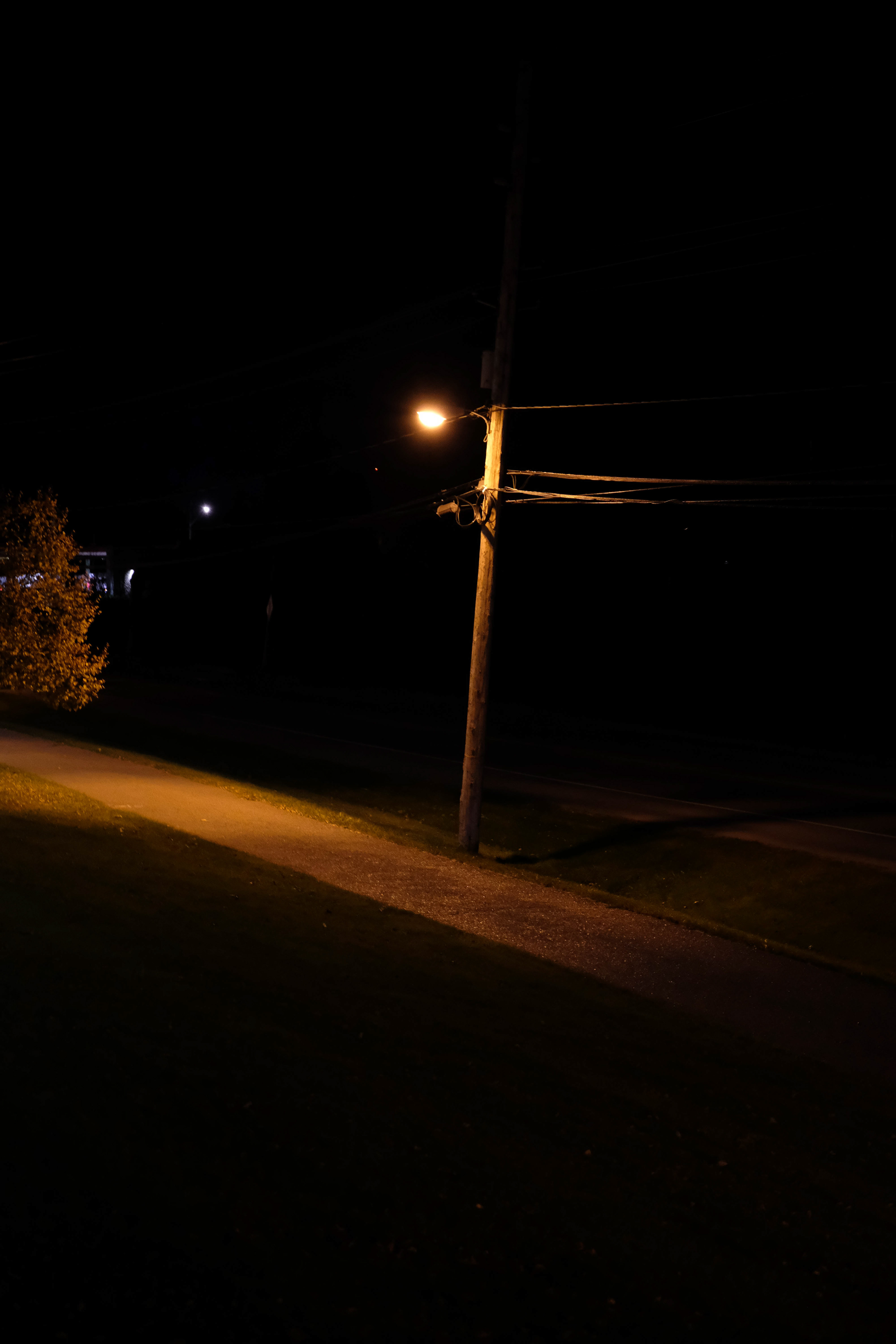 A sidewalk, dimly lit by a street lamp