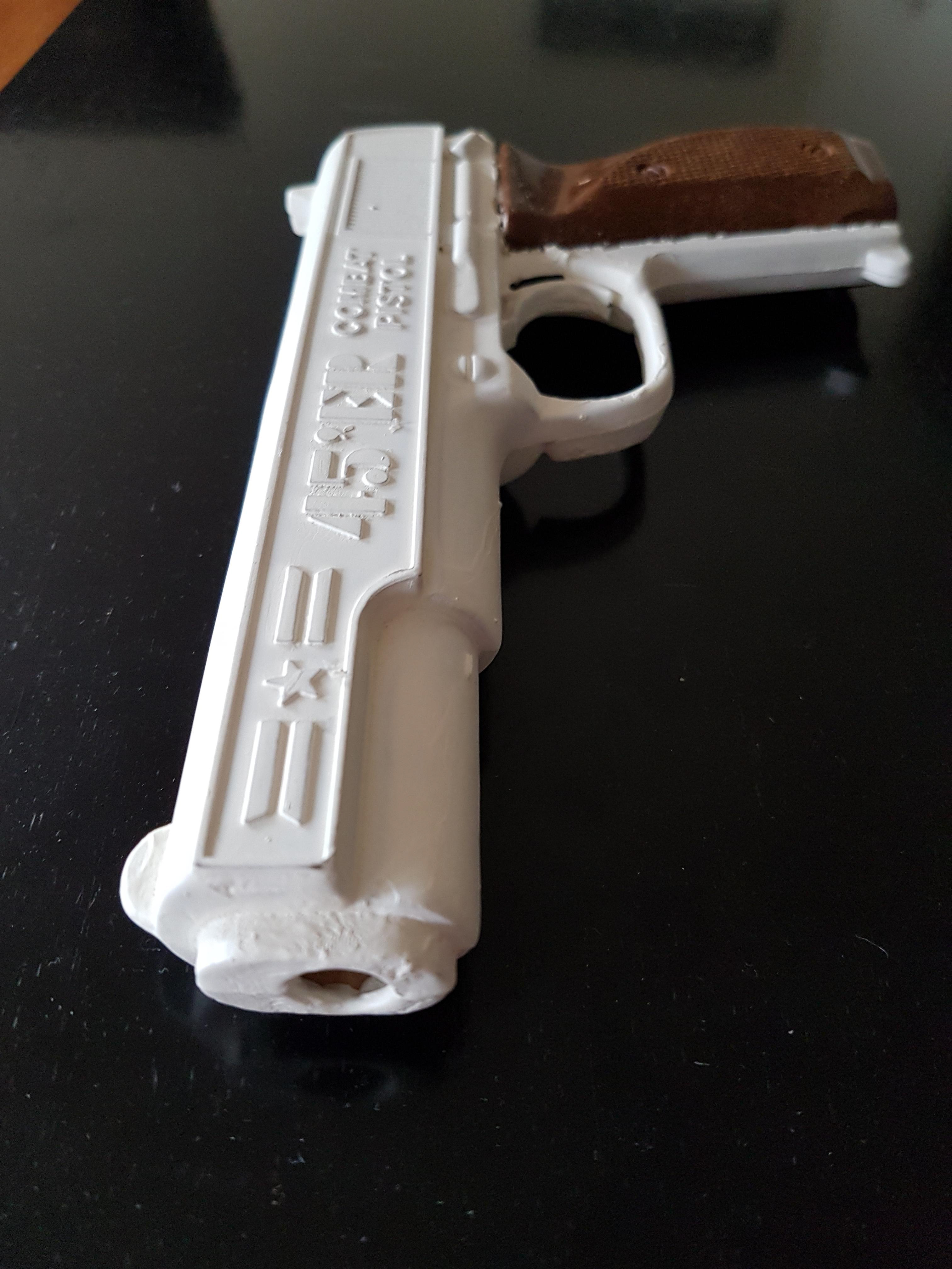 Close up of a realistic plastic toy handgun painted white.