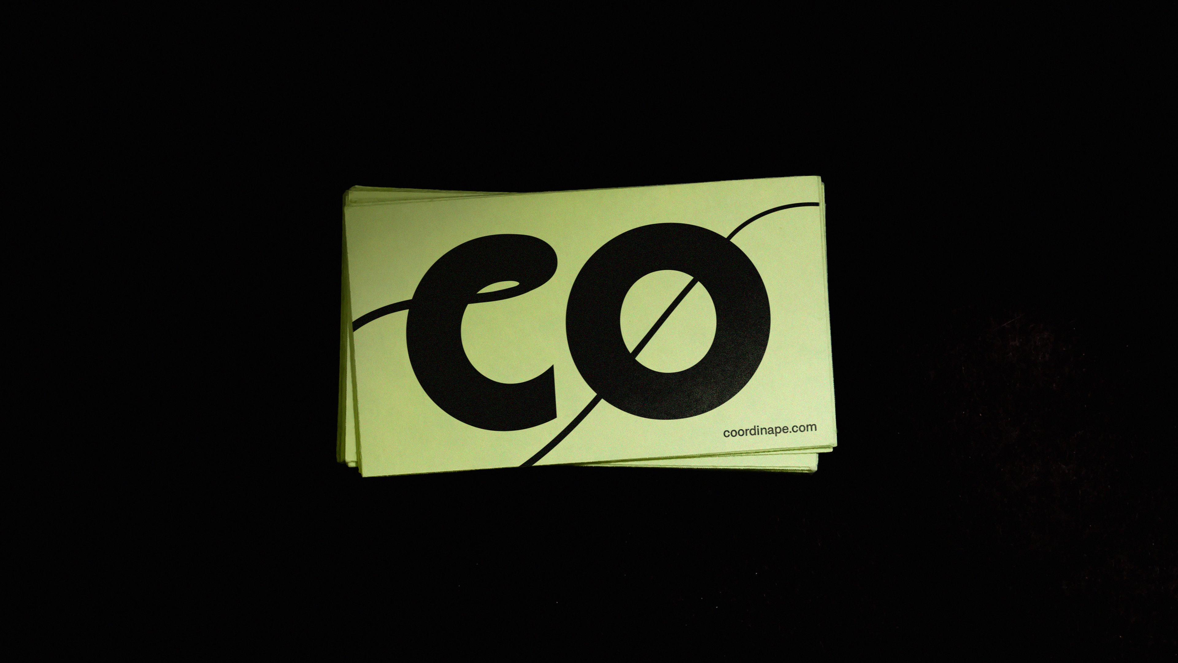 The 'CO' Coordinape monogram logomark on lime green business cards.