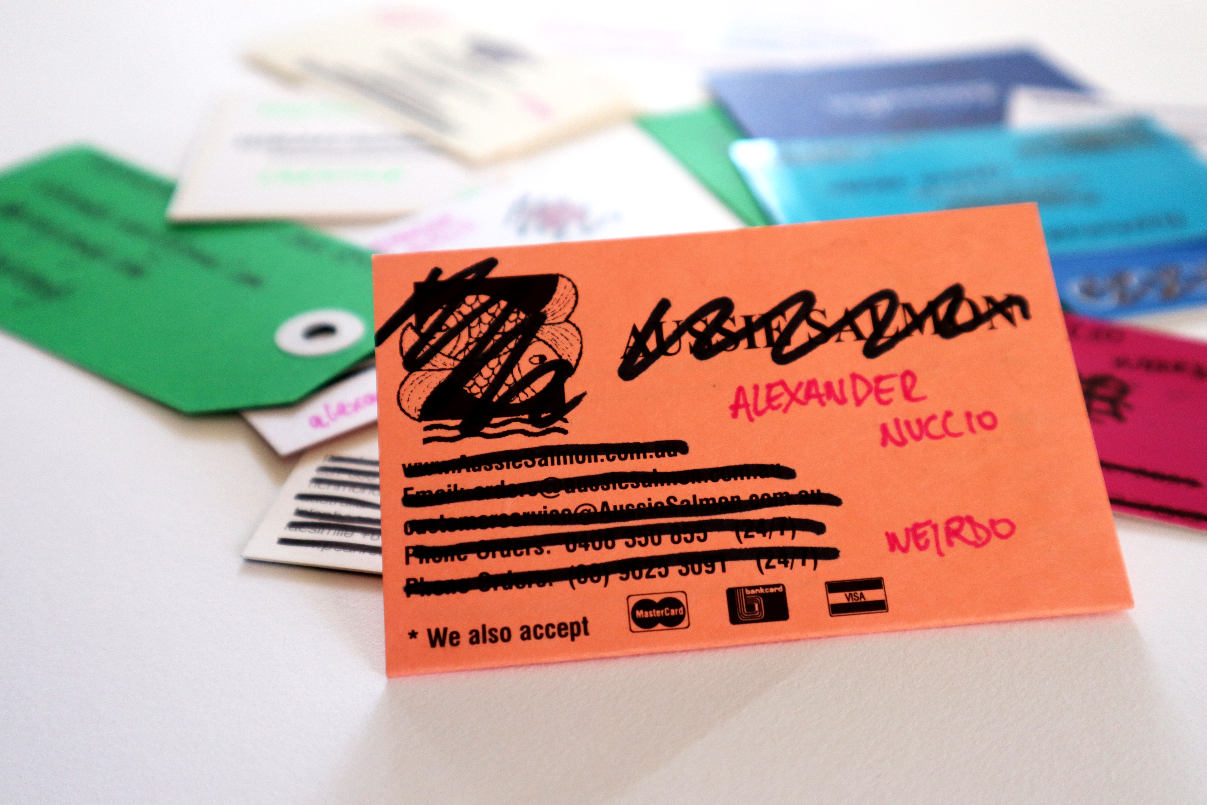 Close up of an orange business card with the original business details crossed out and relatively ready details hand-written in.