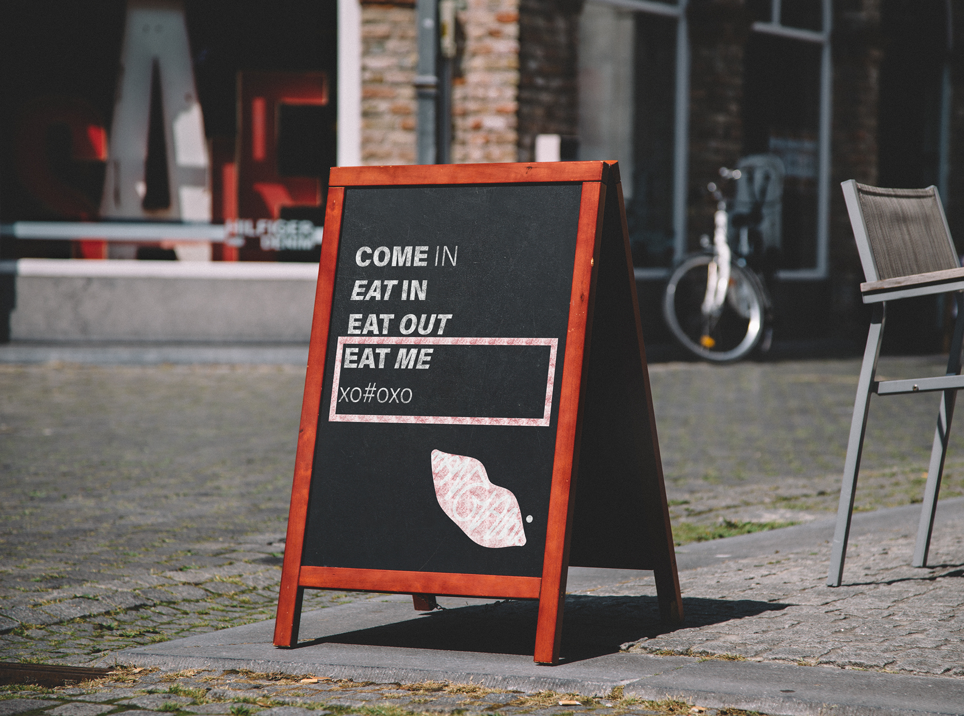 A chalk board on a cobbled-street with the Mangiami tone of voice inviting pizza lovers to 'eat me'.
