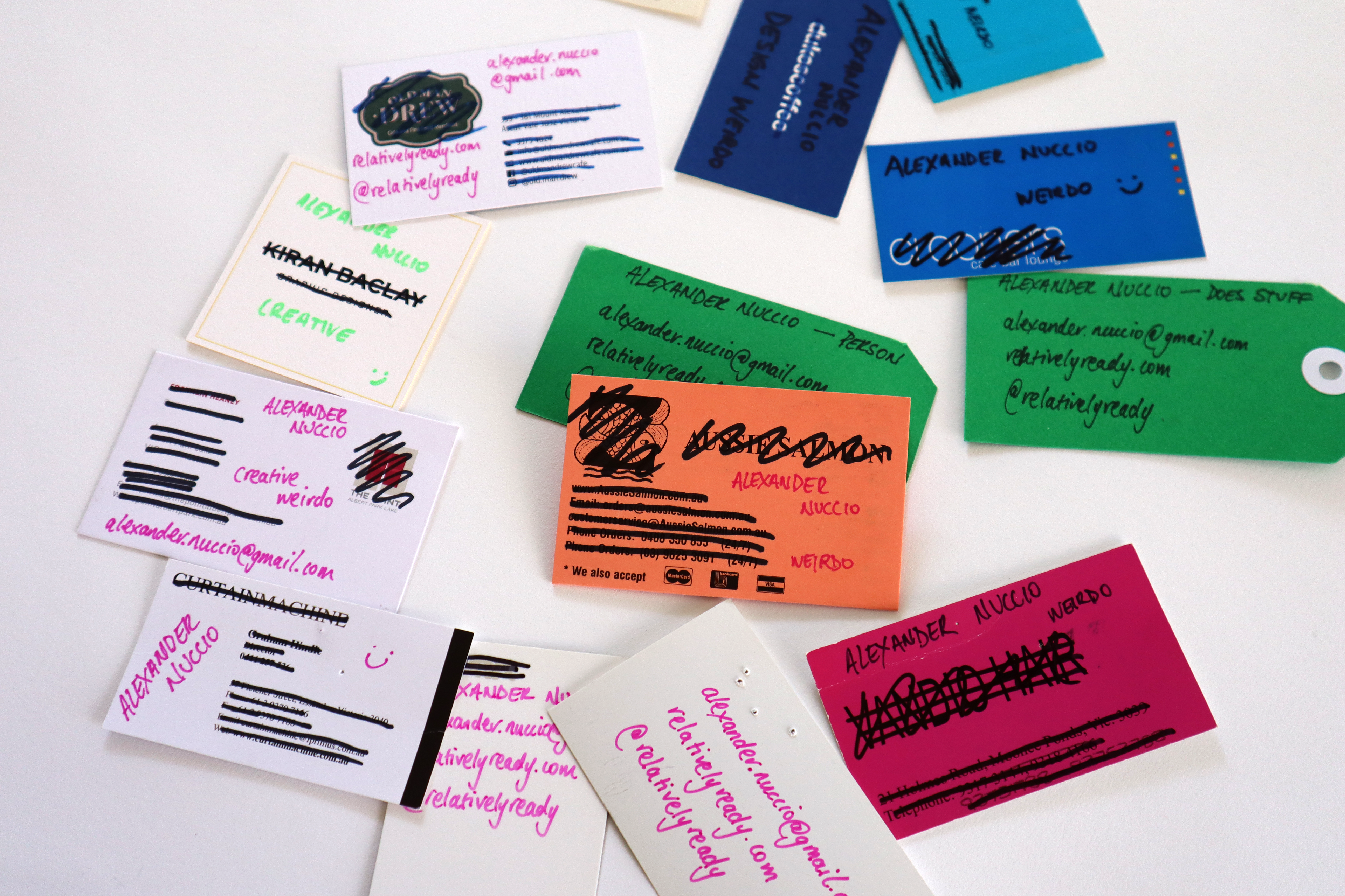 A sprawled pile of business cards with the original business details crossed out and relatively ready details hand-written in.