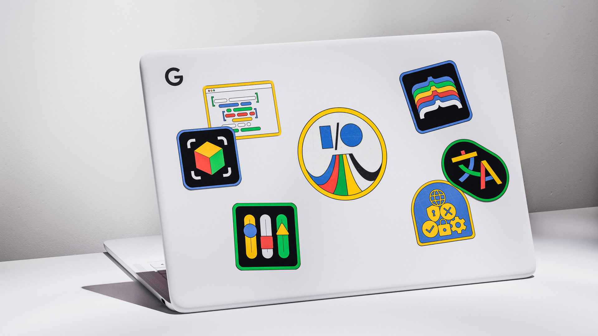 A Google laptop with colourful 60s/70s style stickers pasted all over the lid, alongide an I/O event sticker in the middle.
