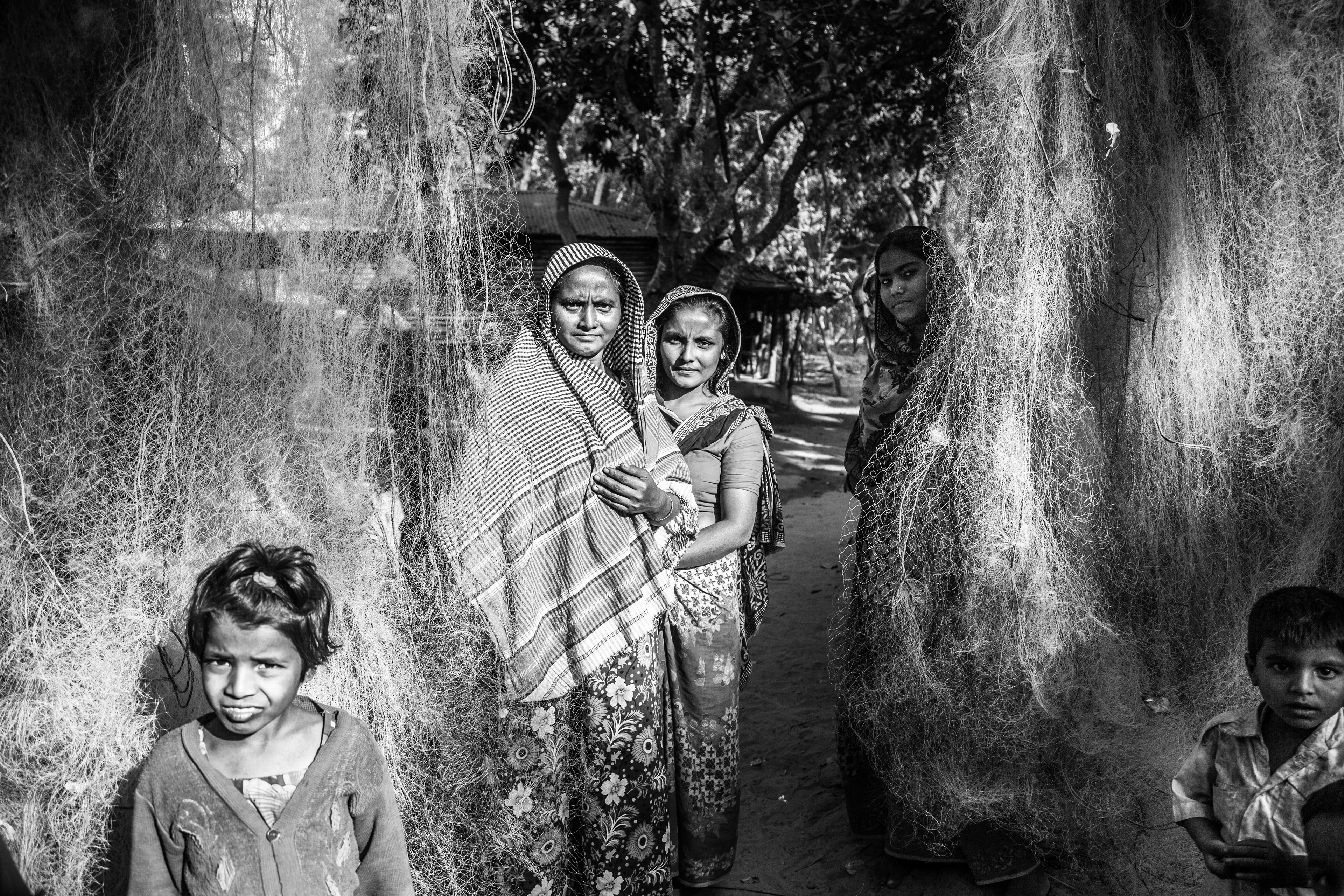 "Fishing Nets." Shamlapur, Bangladesh. Jan 2016. While the men are on boats at sea or working on neighboring farms, the women stay with the children and elders, repairing and drying fishing nets. Rohingyas make up an estimated 5,000-7,000 of the 12,000 residents in this fishing village.