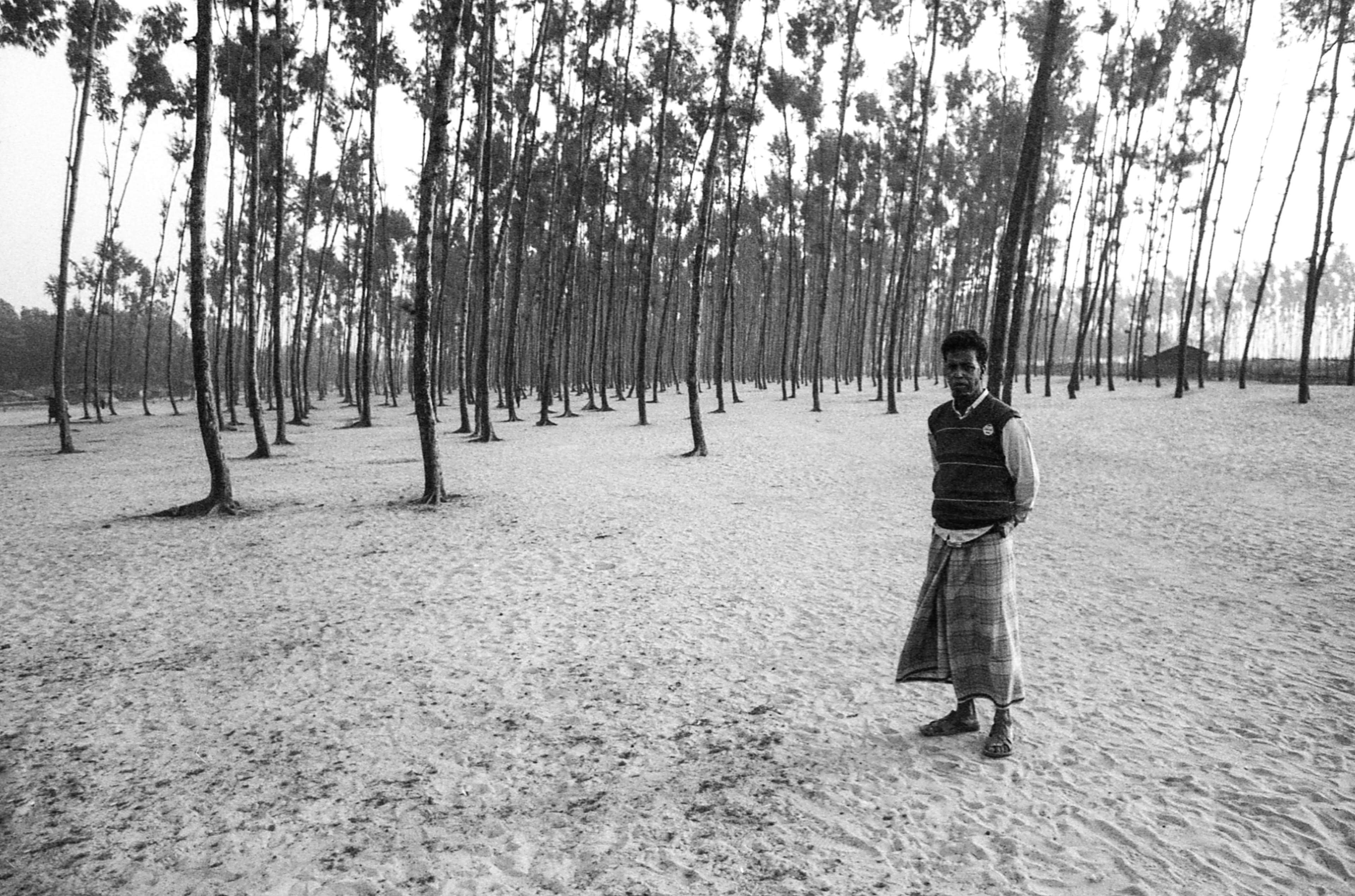 Nazirar Tek, Bangladesh. A Rohingya man stands among the trees at the edge of the village.