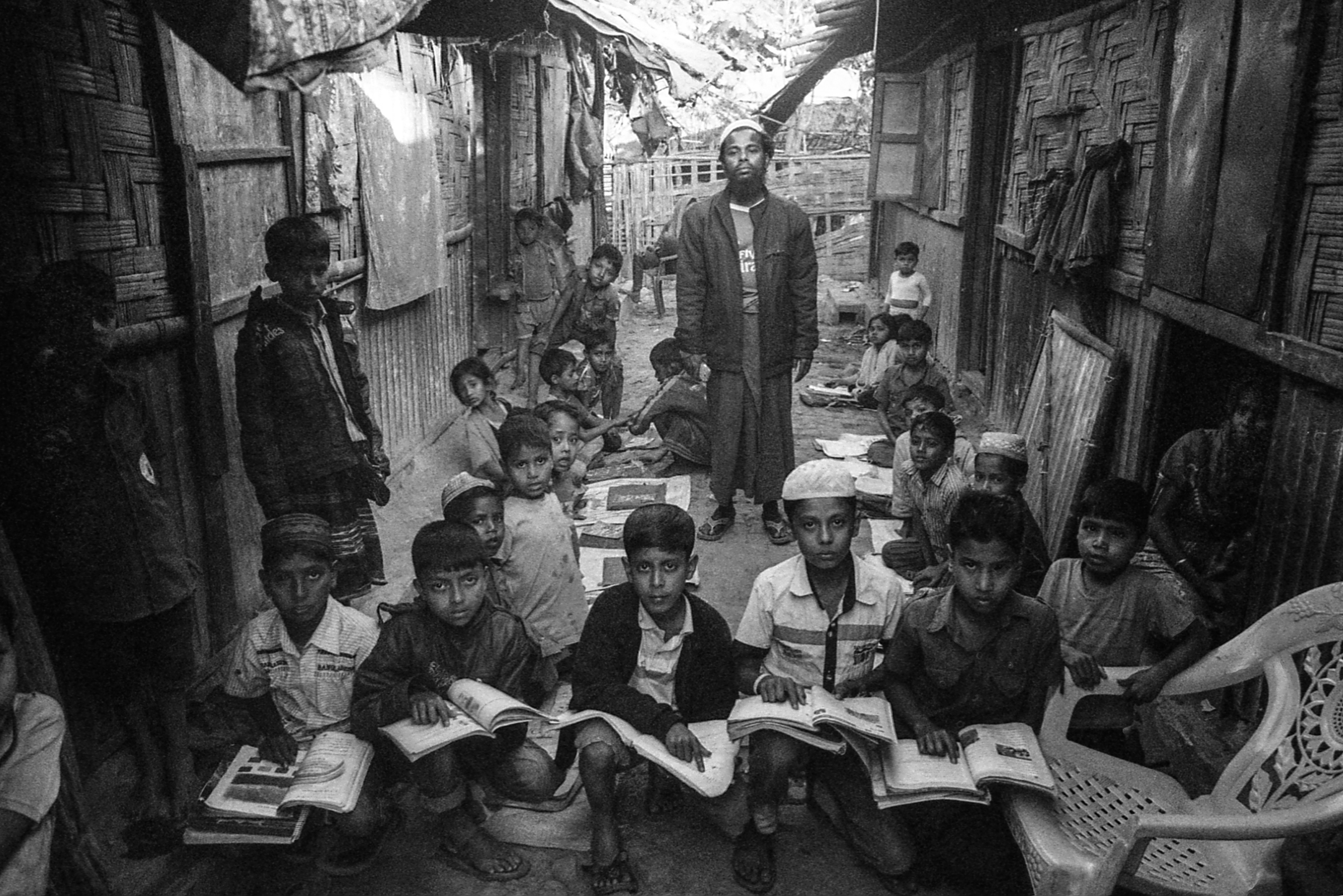 Leda Camp, Teknaf, Bangladesh. With no access to proper educational facilities, many Rohingya families rely on the generosity of teachers like Abdul Majid (center), who offers free lessons outside of his home in the camp.