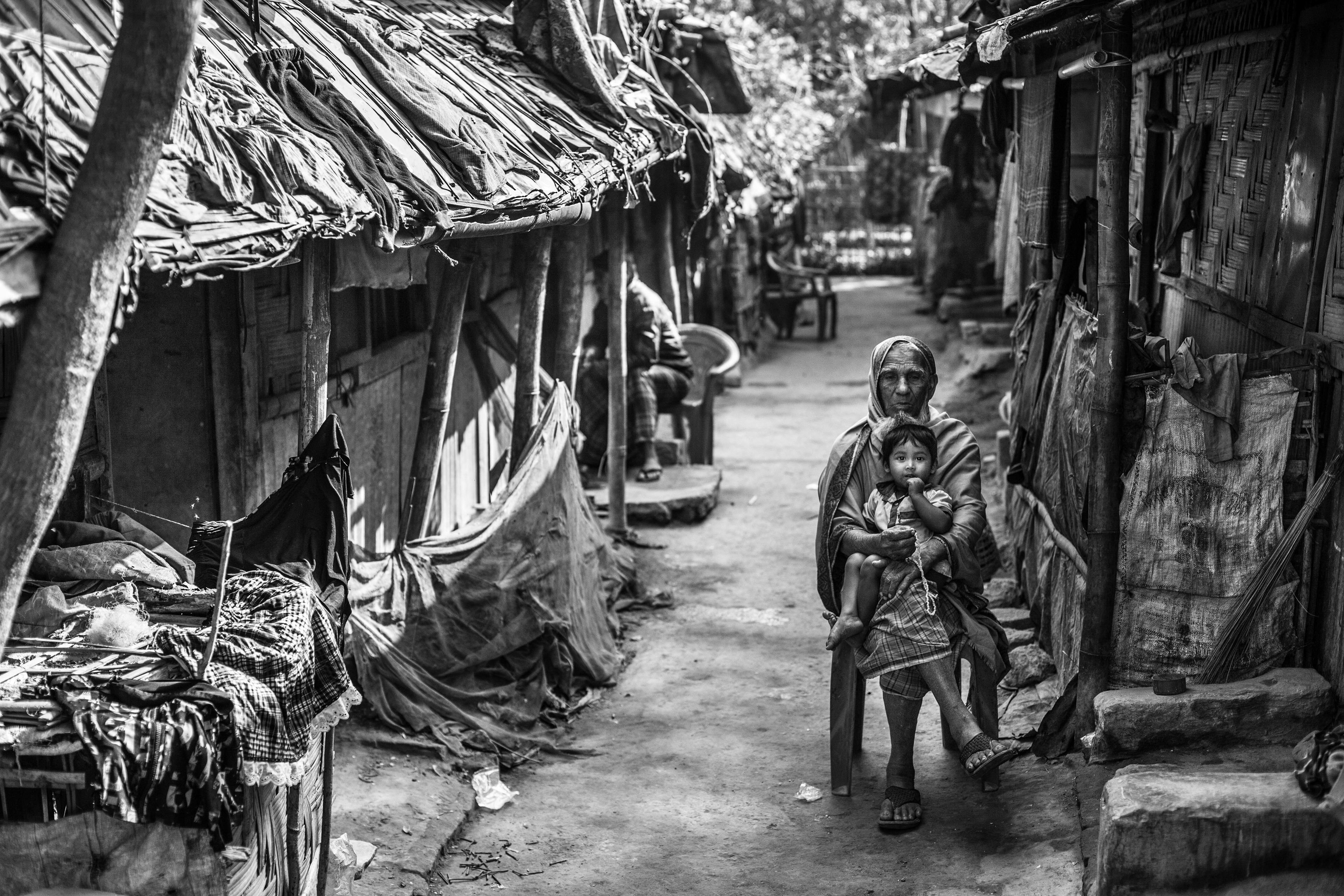 "No Place To Be." Leda Camp, Teknaf, Bangladesh. Jan 2016. A grandfather and his grandson catch some sun in an empty alley while the rest of the family is out. Work is increasingly difficult to find, so most of the day, Rohingyas are out collecting firewood or begging in the neighboring towns.