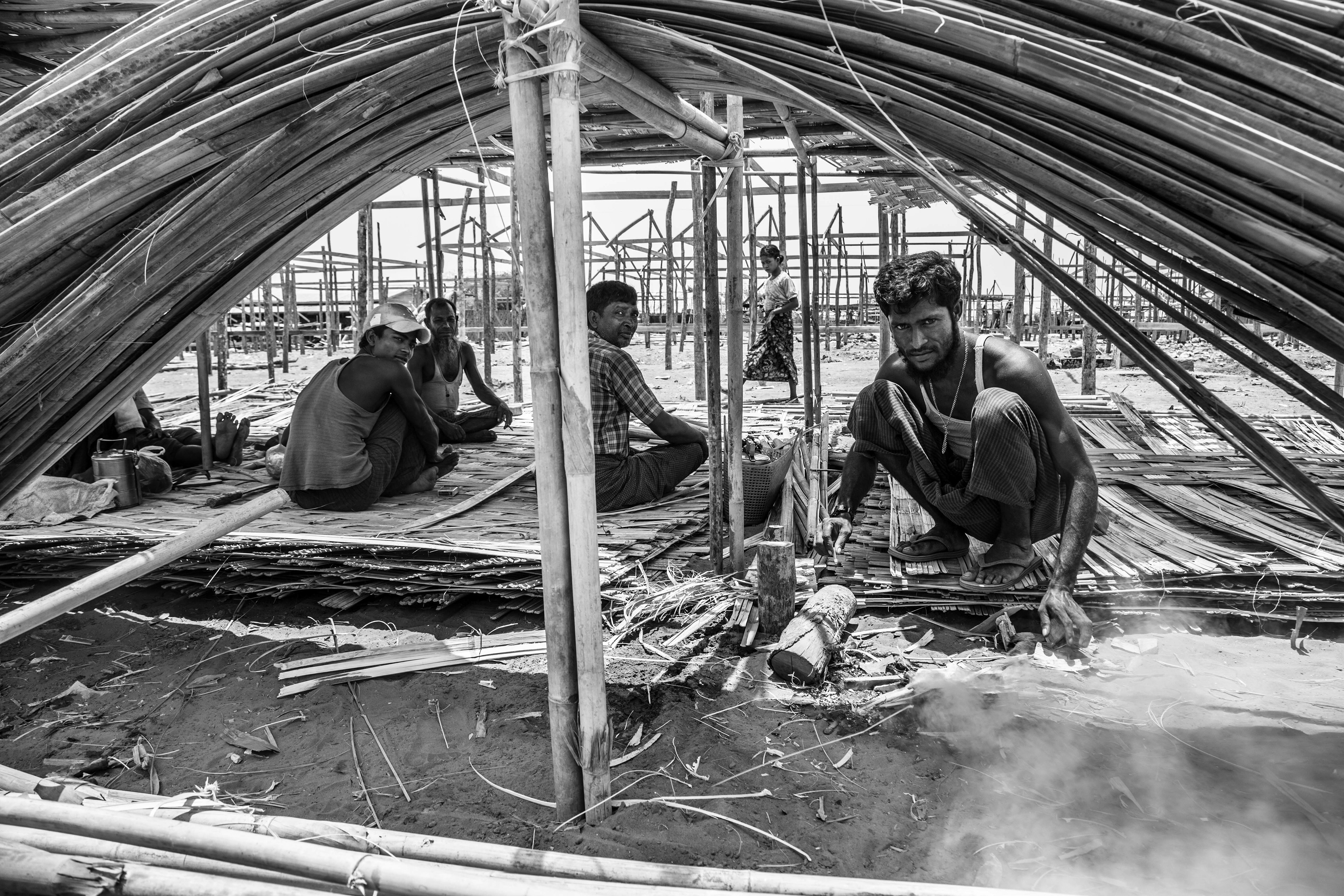 "To Rebuild a Home." Baw Du Ba IDP Camp, Sittwe, Myanmar. May 2016. Following the 2012 violence in downtown Sittwe, thousands of Rohingya were forced out of the city and into isolated IDP (Internally Displaced Persons) camps where they are treated like prisoners. A week before this photo was taken, a devastating fire ripped through the camp, affecting over 400 families. Here, men try to rebuild the longhouses with the little resources that the government has granted them.