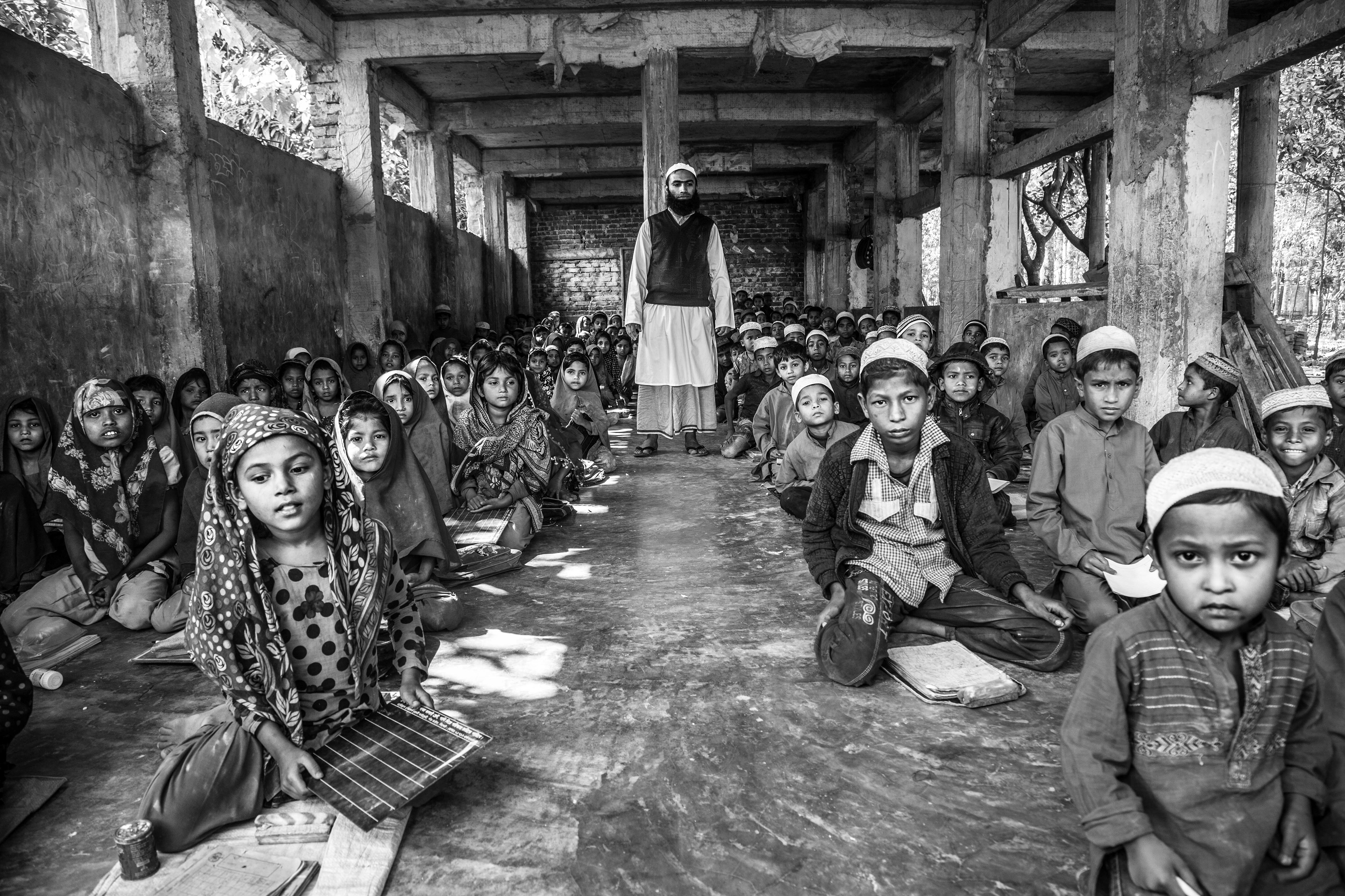 "All Ages Welcome." Shamlapur, Bangladesh. Jan 2016. A group of teachers runs a school here and they allow anyone who can afford the monthly payment of 100 taka (approx. $1 USD) to participate. Lessons include Bengali, English and Arabic languages, math, social sciences and religious studies. They take place six days per week in this unfinished and crumbling building.